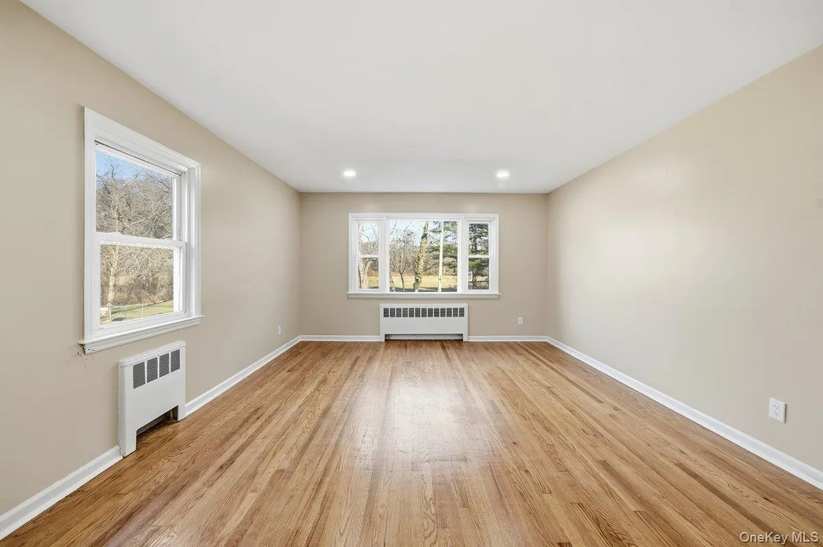 Empty room featuring radiator, light wood-style floors, and recessed lighting Empty room featuring radiator, light wood-style floors, and recessed lighting