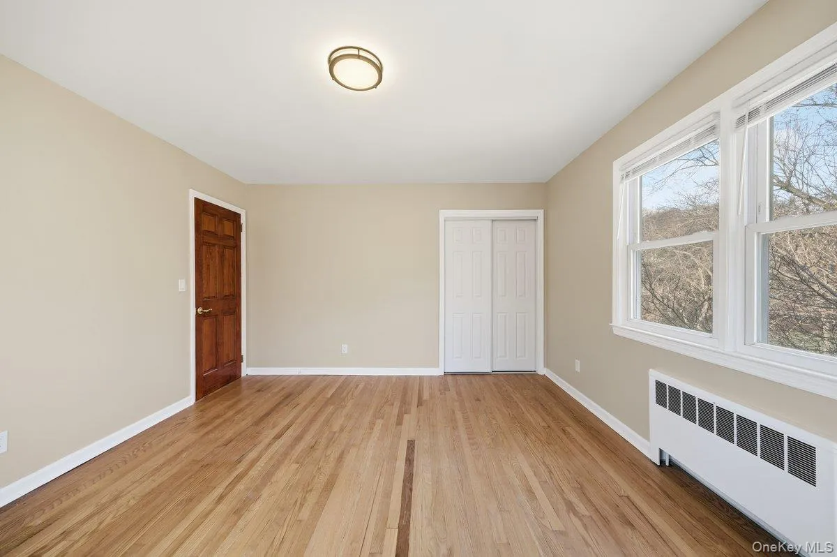 Unfurnished bedroom featuring radiator, a closet, and light wood-style flooring Unfurnished bedroom featuring radiator, a closet, and light wood-style flooring
