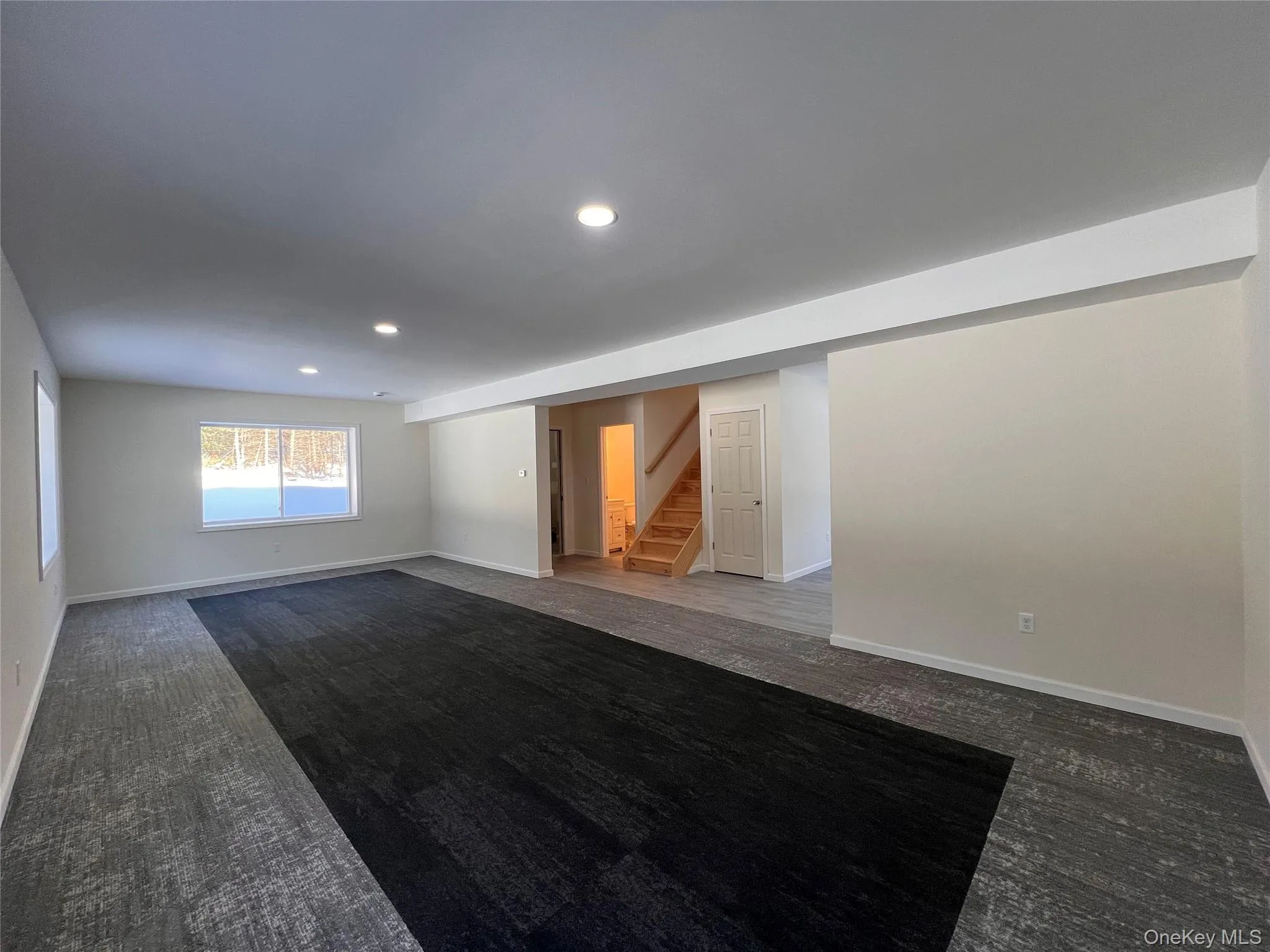 Spare room featuring stairway, recessed lighting, and dark carpet Spare room featuring stairway, recessed lighting, and dark carpet