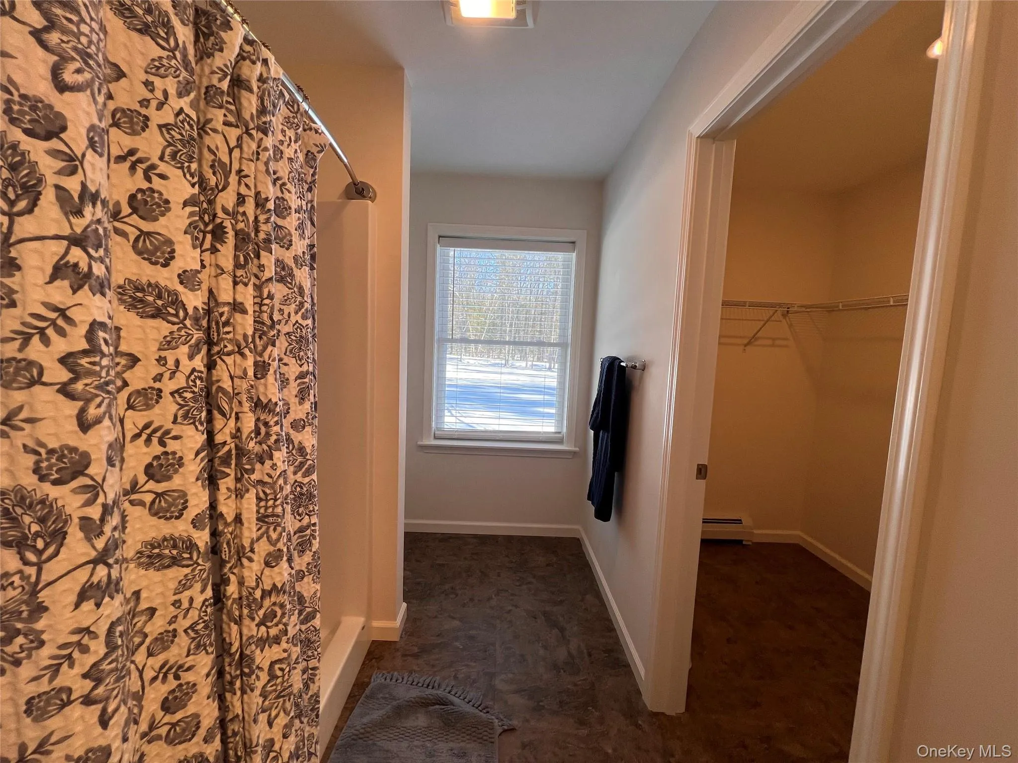 Full bathroom featuring a stall shower, a walk in closet, and a baseboard heating unit Full bathroom featuring a stall shower, a walk in closet, and a baseboard heating unit