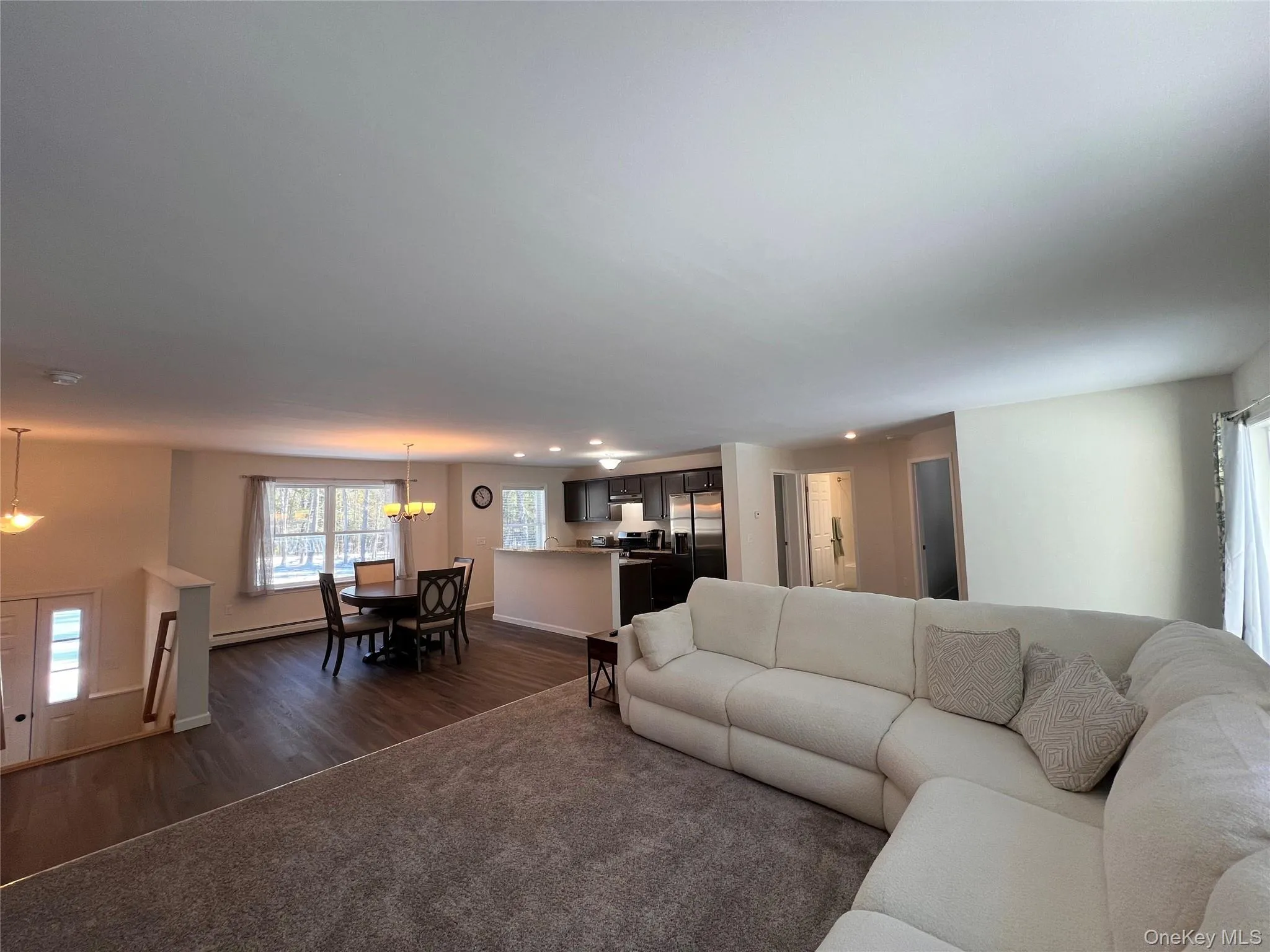 Living area featuring dark wood-type flooring, a baseboard heating unit, recessed lighting, and a chandelier Living area featuring dark wood-type flooring, a baseboard heating unit, recessed lighting, and a chandelier