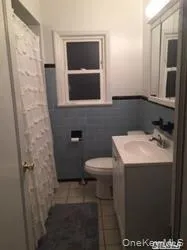 Full bathroom with wainscoting, vanity, a shower with curtain, and dark tile patterned flooring Full bathroom with wainscoting, vanity, a shower with curtain, and dark tile patterned flooring