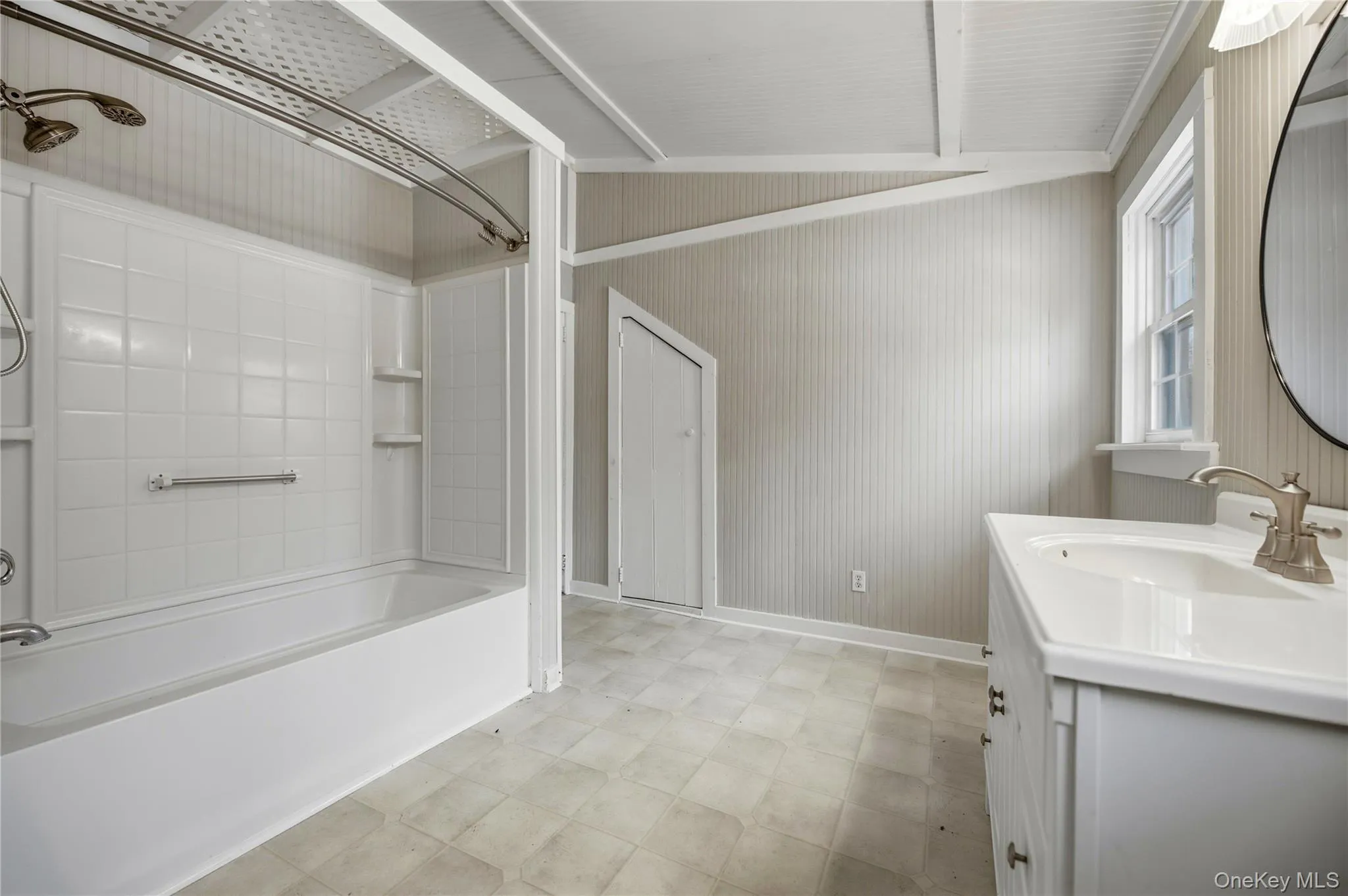 Full bath with bathing tub / shower combination, vanity, vaulted ceiling, and light flooring Full bath with bathing tub / shower combination, vanity, vaulted ceiling, and light flooring