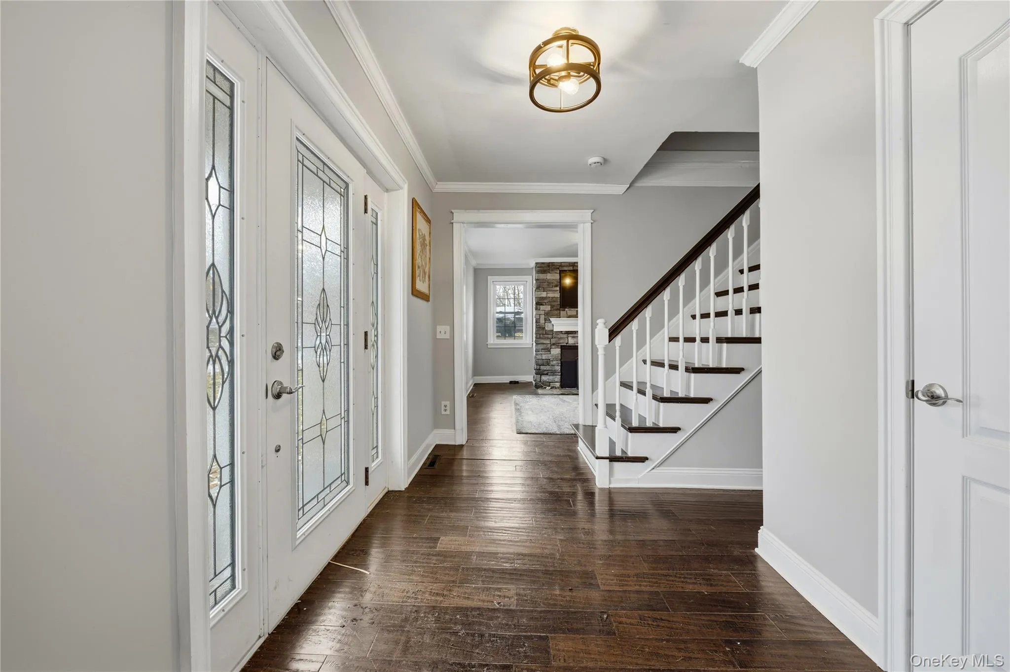 Entryway with crown molding, stairs, and dark wood finished floors Entryway with crown molding, stairs, and dark wood finished floors