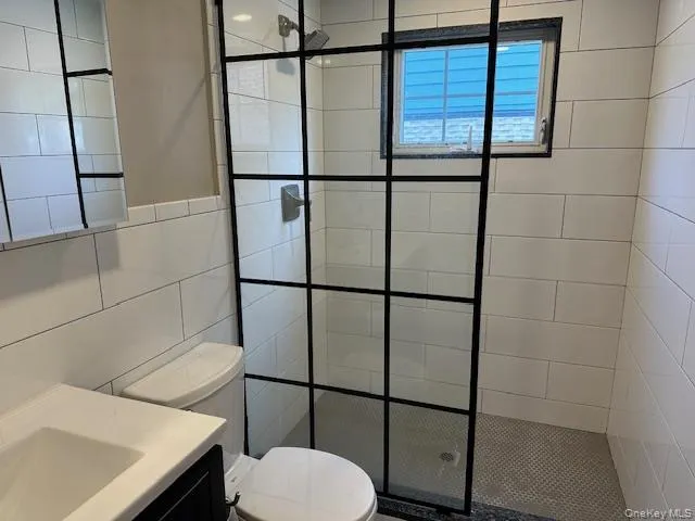 Bathroom with vanity, a walk in shower, and tile walls Bathroom with vanity, a walk in shower, and tile walls