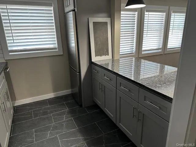 Kitchen with dark stone countertops, stainless steel refrigerator, and plenty of natural light Kitchen with dark stone countertops, stainless steel refrigerator, and plenty of natural light