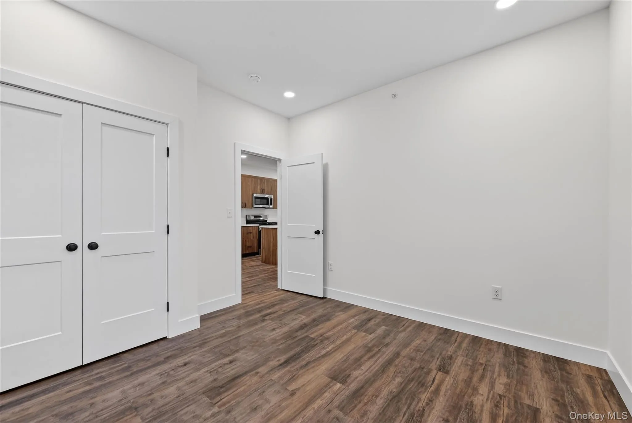 Unfurnished bedroom with a closet, recessed lighting, and dark wood-style floors Unfurnished bedroom with a closet, recessed lighting, and dark wood-style floors