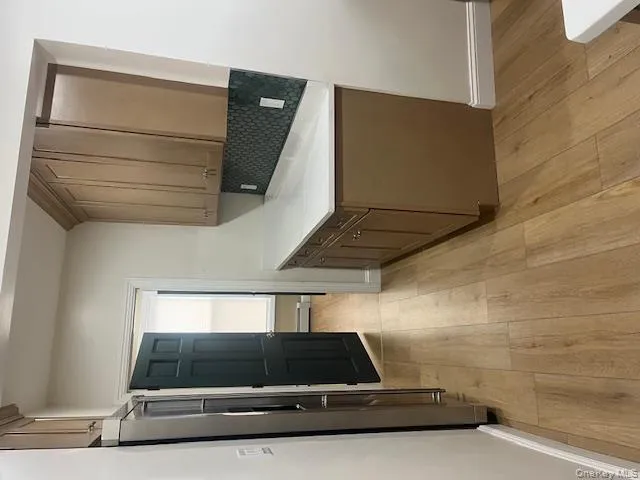 Kitchen with light stone counters, light wood-style floors, fridge, tasteful backsplash, and a baseboard heating unit Kitchen with light stone counters, light wood-style floors, fridge, tasteful backsplash, and a baseboard heating unit