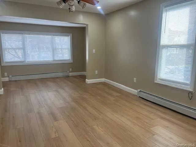 Empty room featuring light wood-style floors, a baseboard radiator, recessed lighting, and a ceiling fan Empty room featuring light wood-style floors, a baseboard radiator, recessed lighting, and a ceiling fan