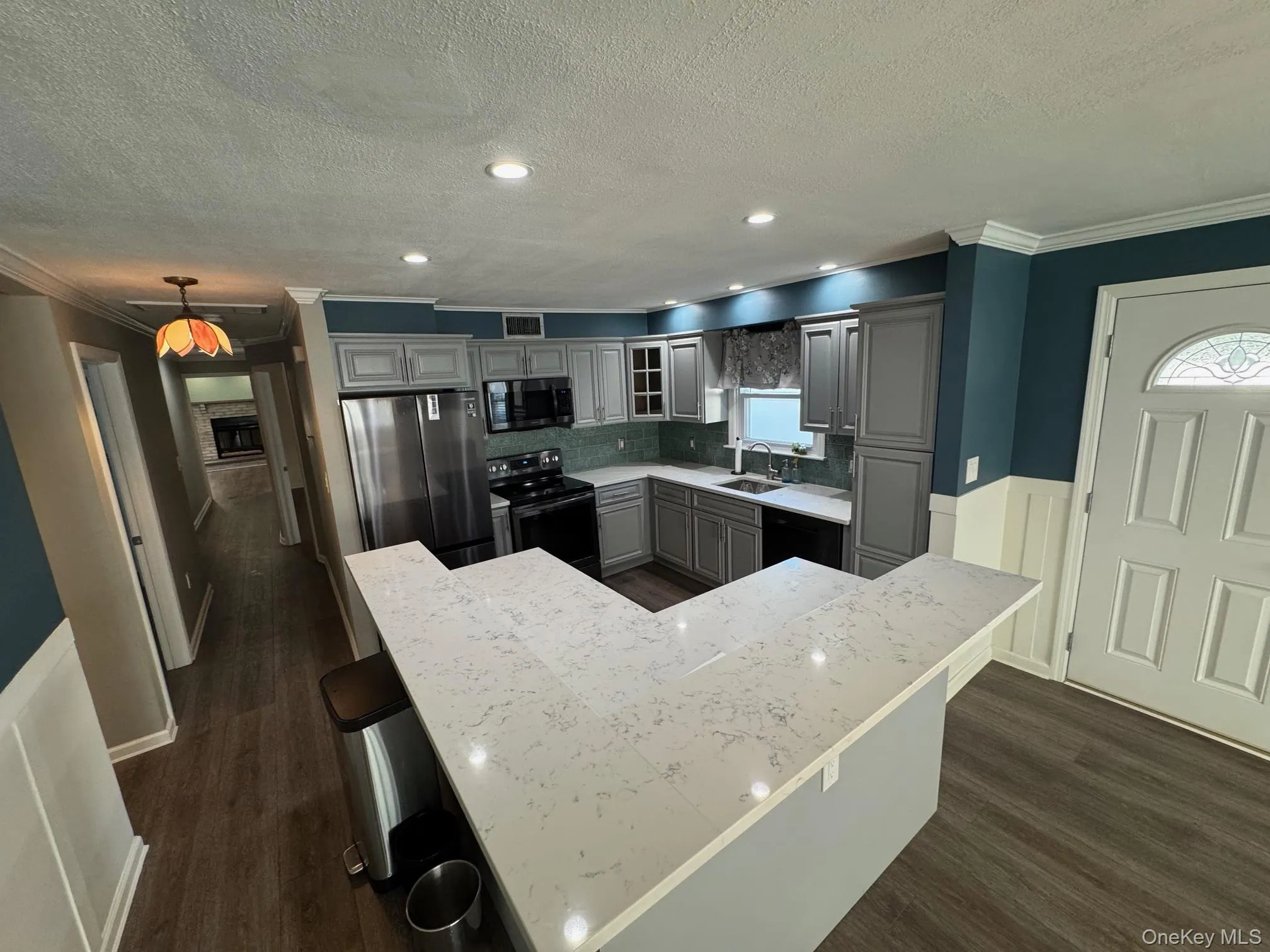 Kitchen featuring ornamental molding, black appliances, gray cabinets, a breakfast bar area, and recessed lighting Kitchen featuring ornamental molding, black appliances, gray cabinets, a breakfast bar area, and recessed lighting