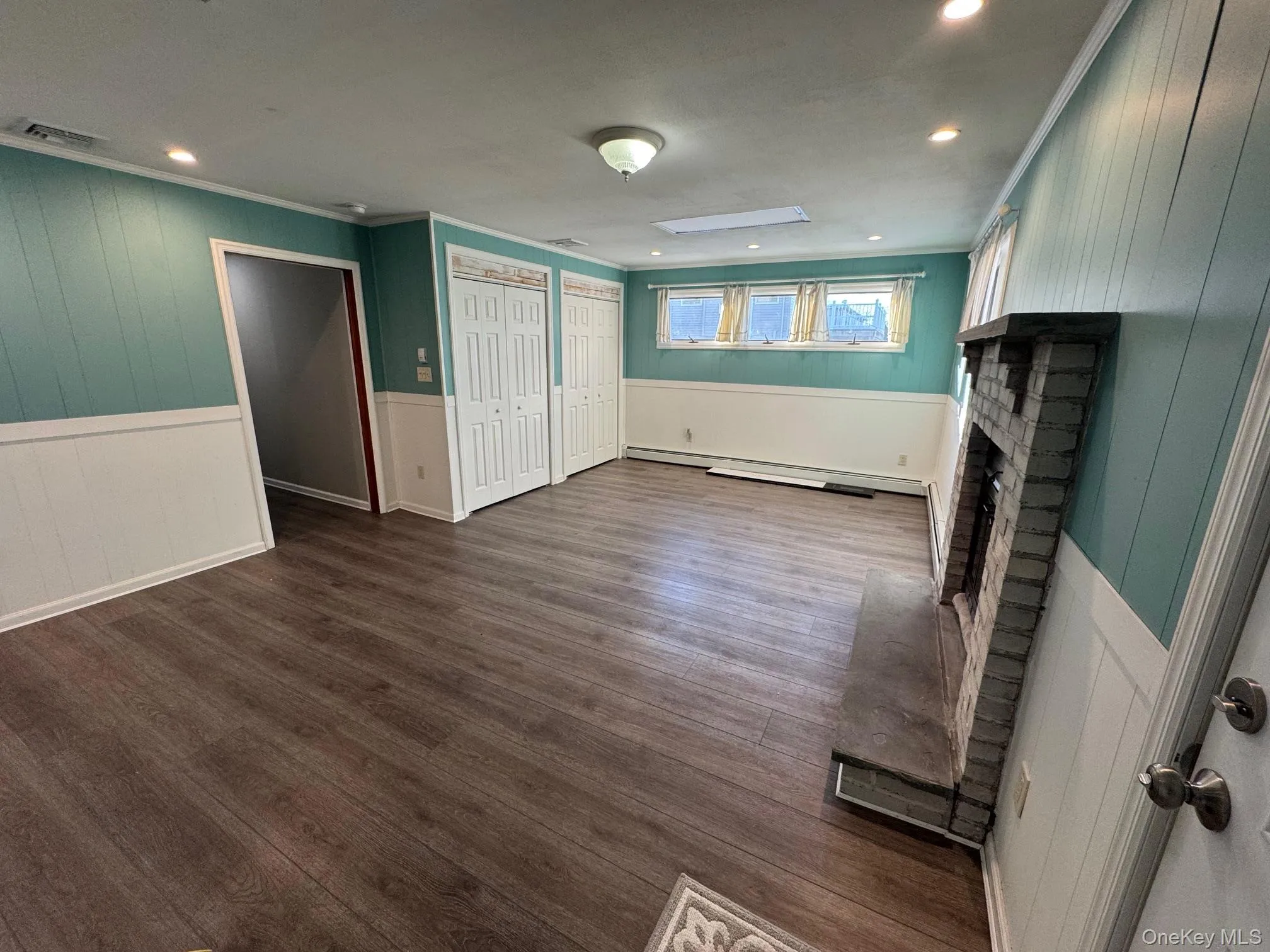 Unfurnished living room with a wainscoted wall, wooden walls, dark wood-style flooring, a decorative wall, and a fireplace Unfurnished living room with a wainscoted wall, wooden walls, dark wood-style flooring, a decorative wall, and a fireplace