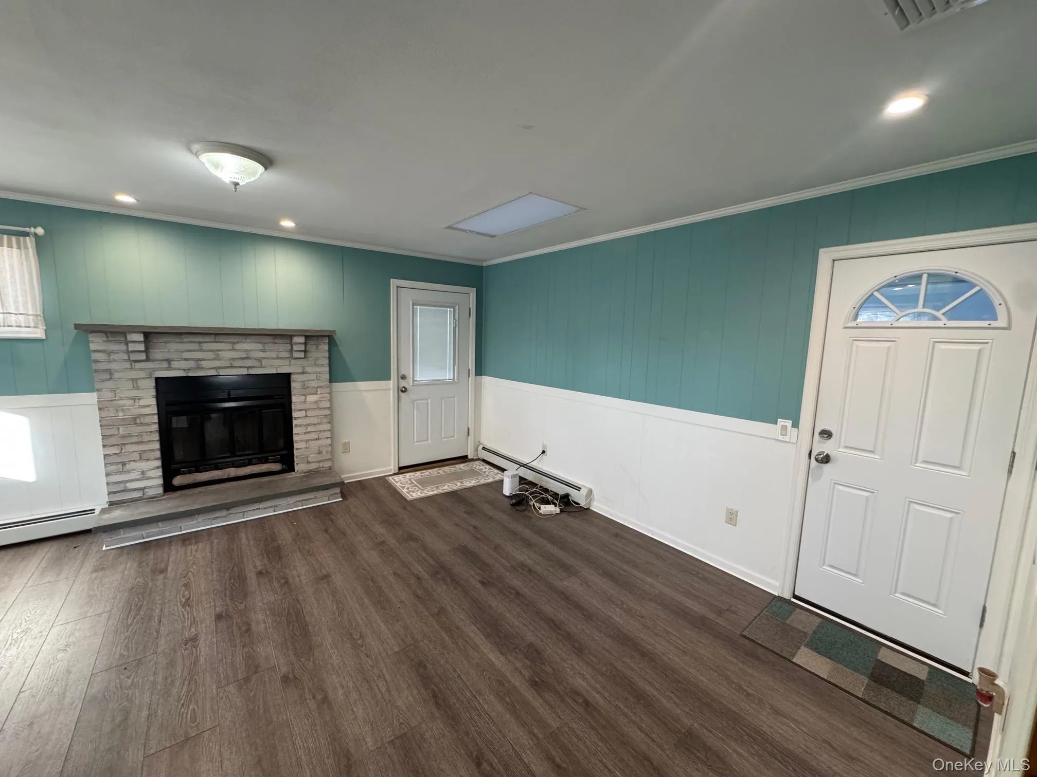 Unfurnished living room with wooden walls, dark wood-style floors, a baseboard radiator, a fireplace, and recessed lighting Unfurnished living room with wooden walls, dark wood-style floors, a baseboard radiator, a fireplace, and recessed lighting