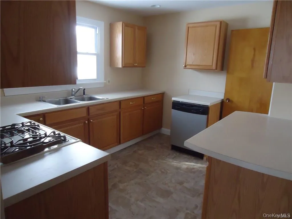 Kitchen featuring dishwasher, a sink, stovetop, light countertops, and light floors Kitchen featuring dishwasher, a sink, stovetop, light countertops, and light floors
