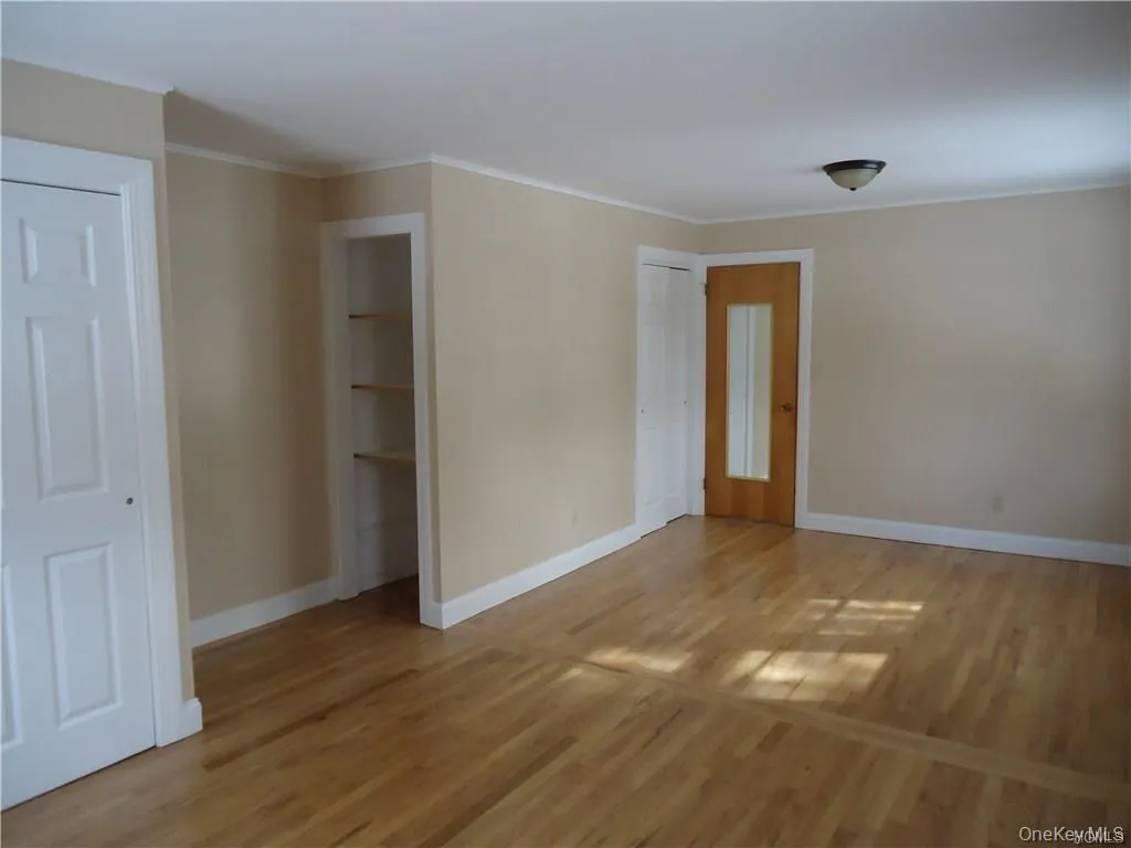 Spare room featuring baseboards, light wood finished floors, and crown molding Spare room featuring baseboards, light wood finished floors, and crown molding