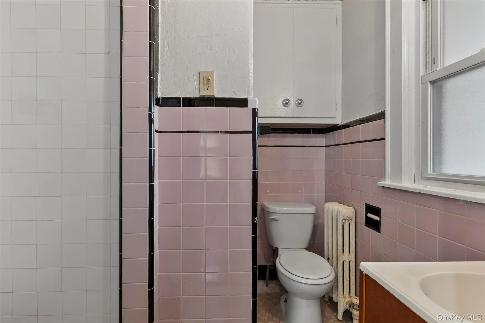 Bathroom with radiator heating unit, tile walls, vanity, and a textured wall Bathroom with radiator heating unit, tile walls, vanity, and a textured wall