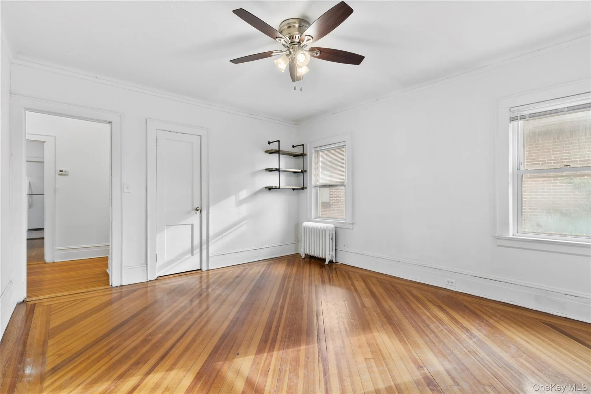 Unfurnished bedroom with radiator, ceiling fan, ornamental molding, and hardwood / wood-style flooring Unfurnished bedroom with radiator, ceiling fan, ornamental molding, and hardwood / wood-style flooring