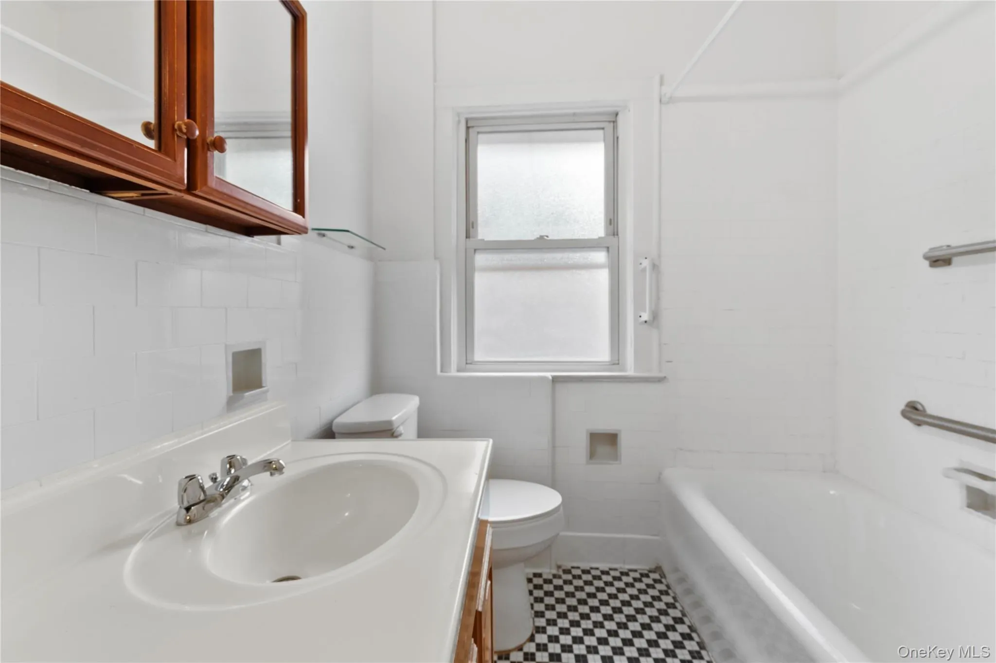 Full bathroom featuring vanity, tile walls, a wainscoted wall, and bathing tub / shower combination Full bathroom featuring vanity, tile walls, a wainscoted wall, and bathing tub / shower combination