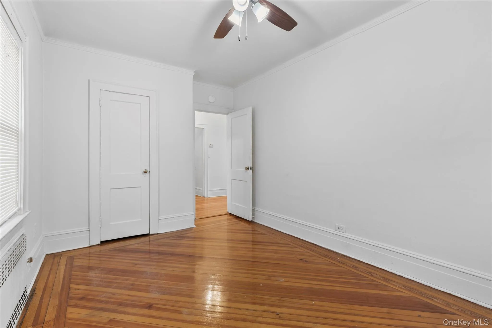 Unfurnished bedroom featuring wood-type flooring, ceiling fan, and crown molding Unfurnished bedroom featuring wood-type flooring, ceiling fan, and crown molding