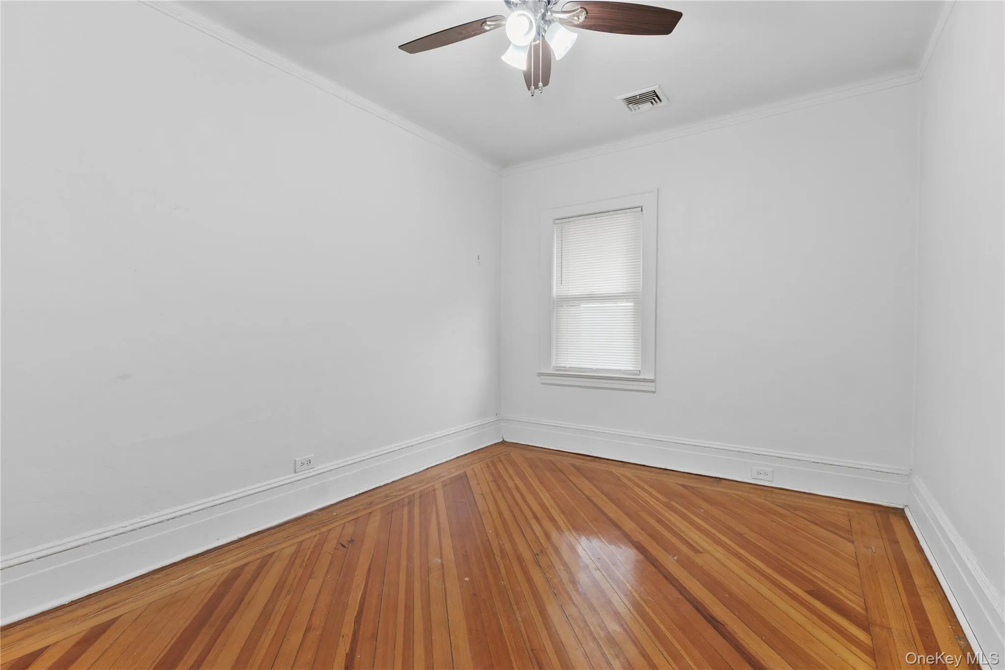 Empty room with ornamental molding, wood-type flooring, and a ceiling fan Empty room with ornamental molding, wood-type flooring, and a ceiling fan