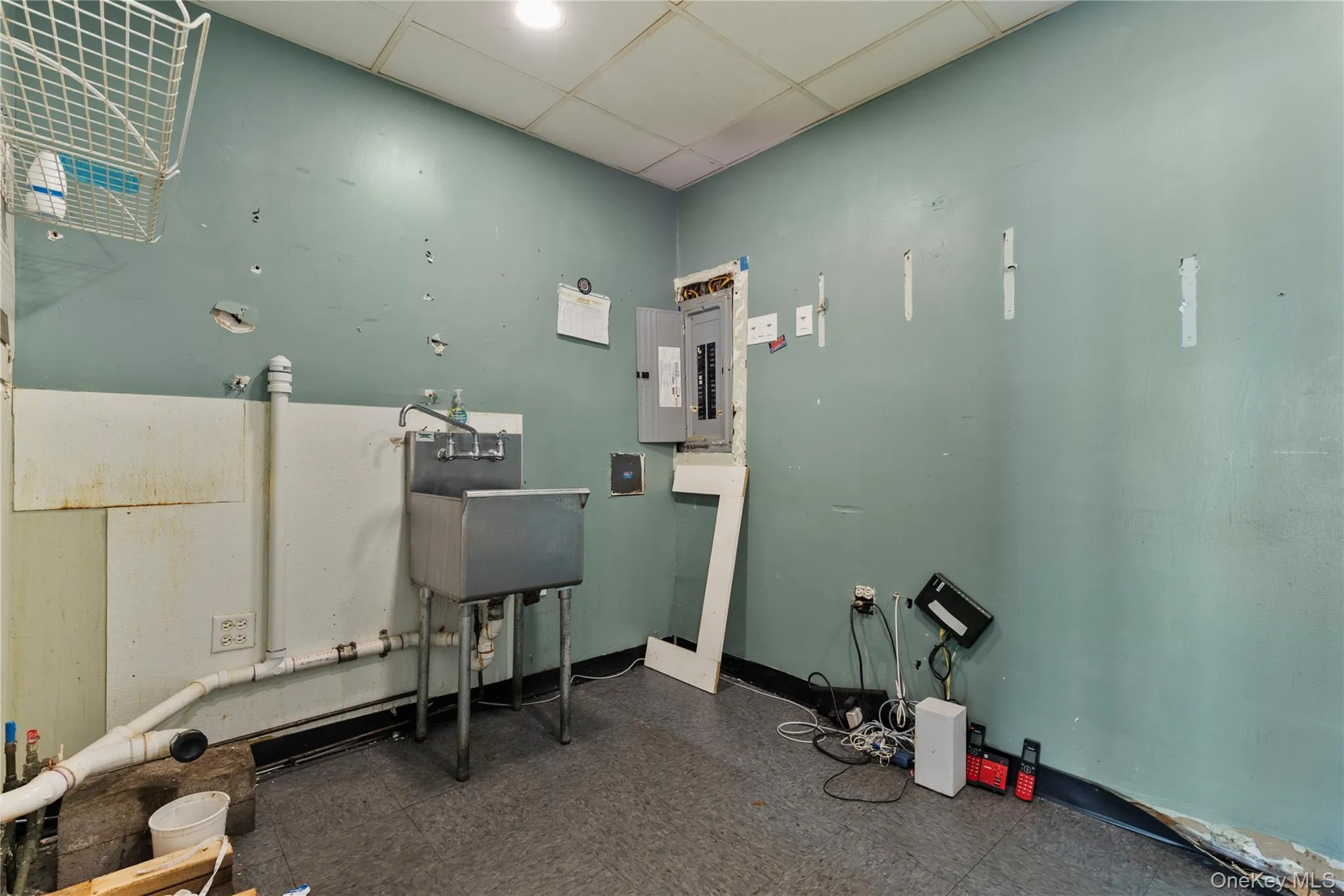 Miscellaneous room featuring a drop ceiling and electric panel Miscellaneous room featuring a drop ceiling and electric panel