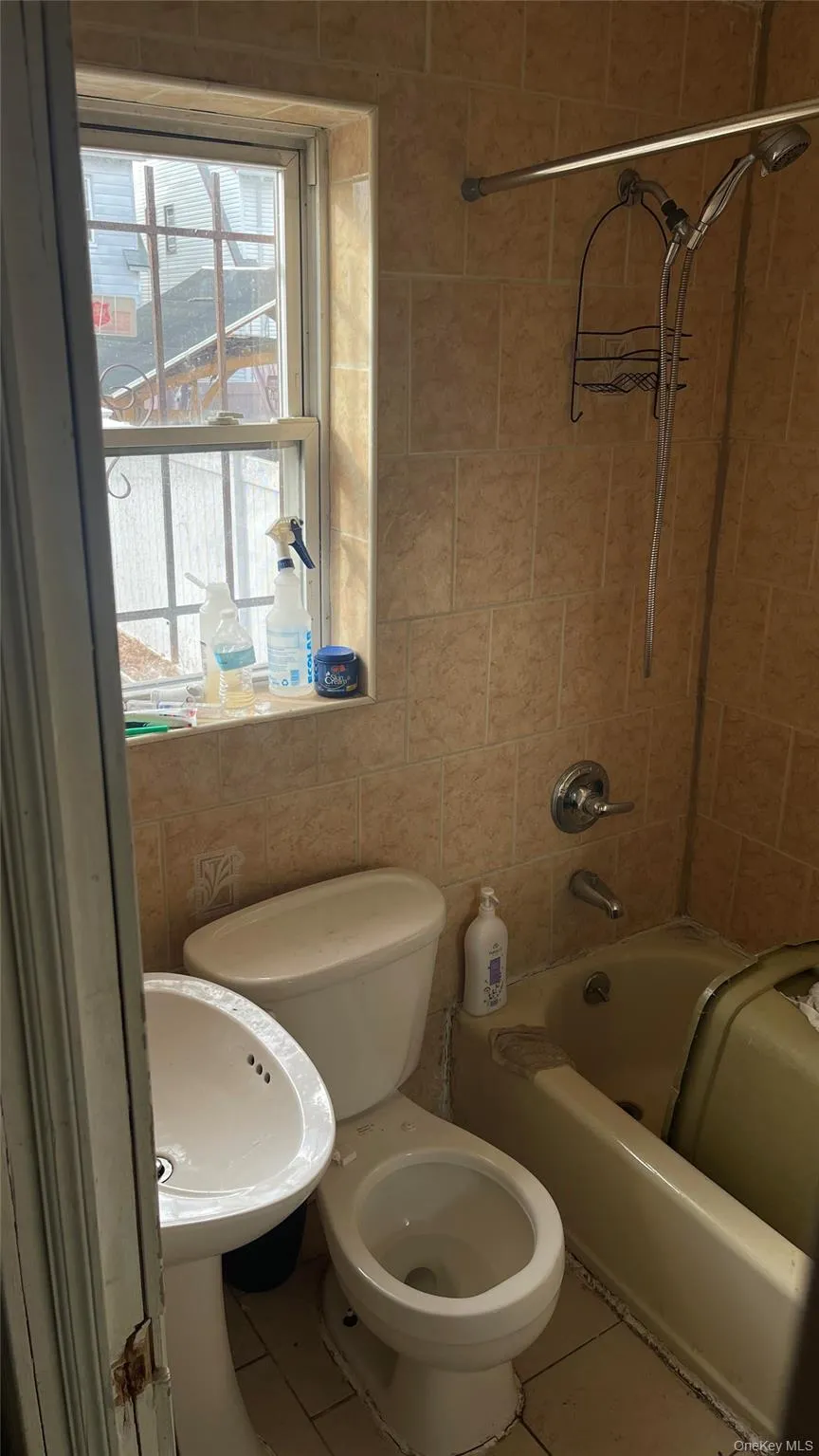 Full bath with bathtub / shower combination, tile patterned floors, and tile walls Full bath with bathtub / shower combination, tile patterned floors, and tile walls