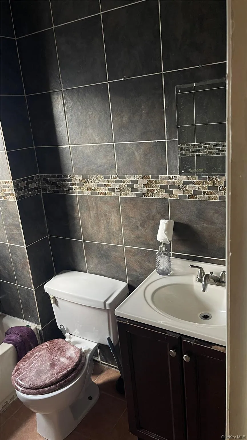 Bathroom featuring tile walls, vanity, and tile patterned floors Bathroom featuring tile walls, vanity, and tile patterned floors