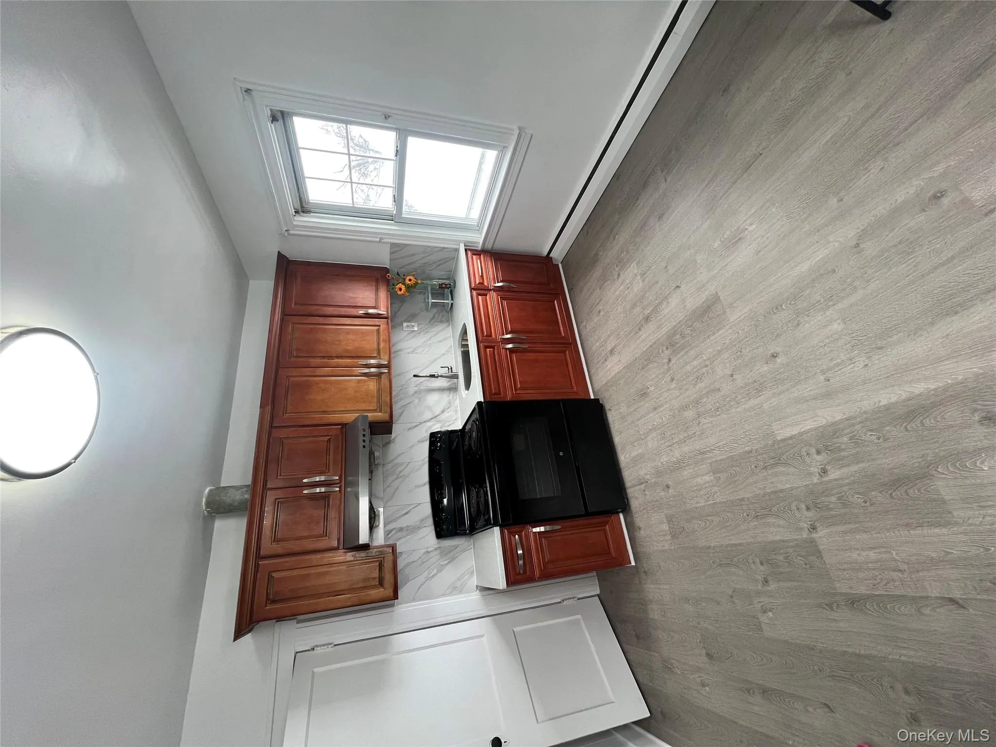 Kitchen with stove, a baseboard heating unit, light wood-style floors, tasteful backsplash, and ventilation hood Kitchen with stove, a baseboard heating unit, light wood-style floors, tasteful backsplash, and ventilation hood