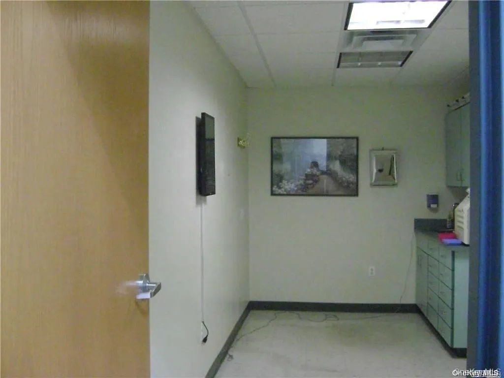Hall featuring baseboards and a drop ceiling Hall featuring baseboards and a drop ceiling