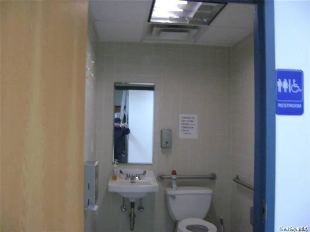Half bathroom featuring toilet and tile walls Half bathroom featuring toilet and tile walls