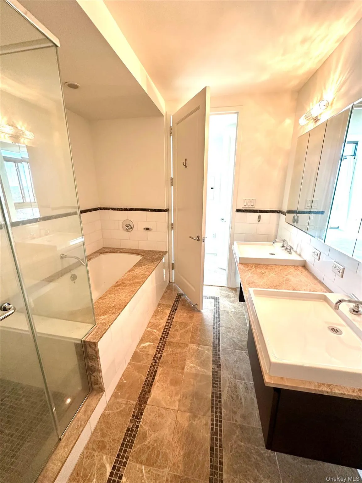 Full bathroom with plenty of natural light, double vanity, a garden tub, and inlaid floor details Full bathroom with plenty of natural light, double vanity, a garden tub, and inlaid floor details