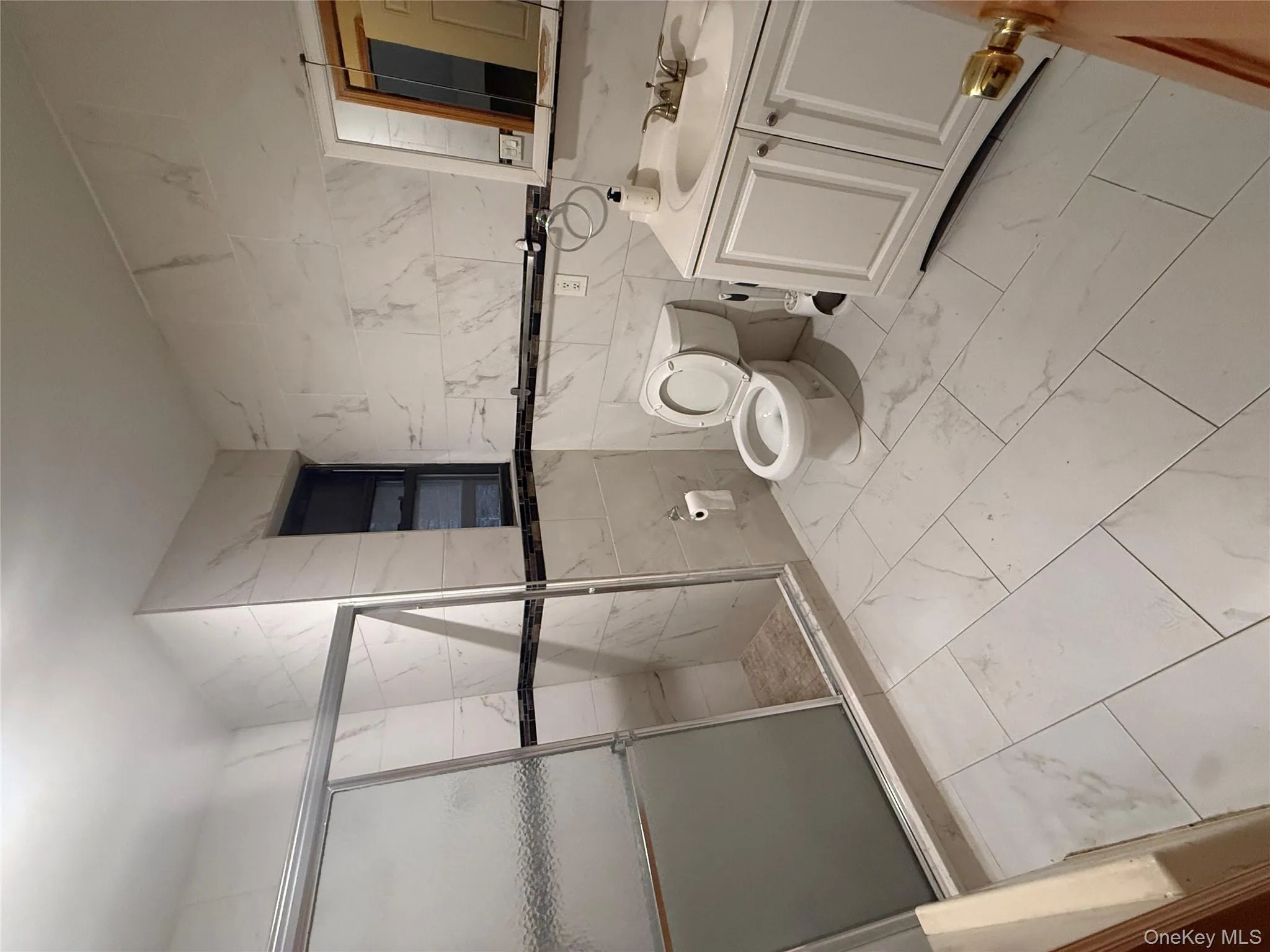Bathroom featuring tile walls, vanity, light marble finish floors, and a shower stall Bathroom featuring tile walls, vanity, light marble finish floors, and a shower stall