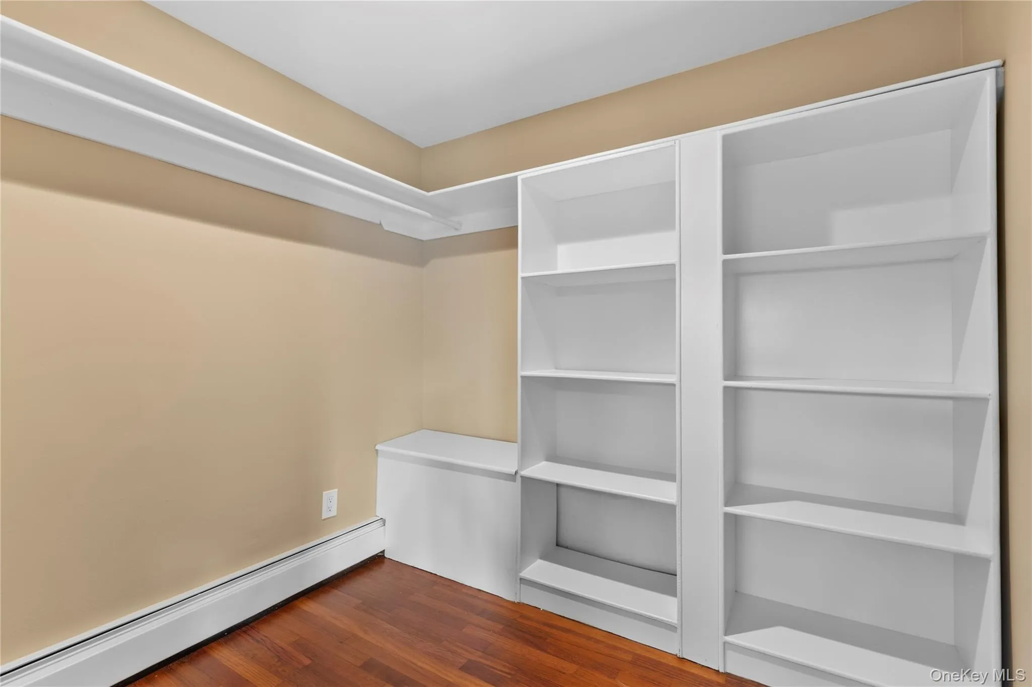 Spacious closet with a baseboard heating unit and dark wood-style floors Spacious closet with a baseboard heating unit and dark wood-style floors