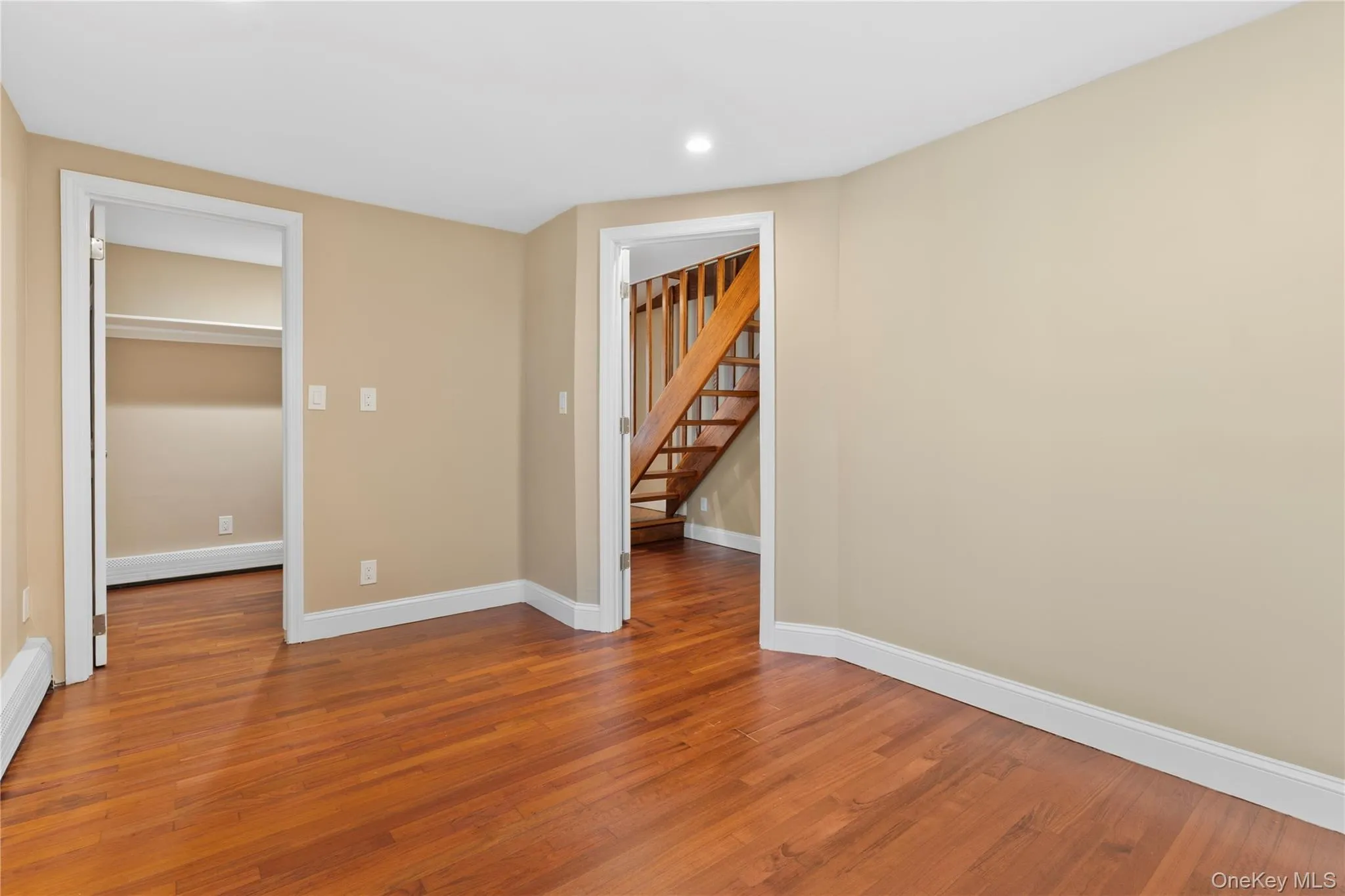 Unfurnished bedroom with wood finished floors, recessed lighting, baseboard heating, and a baseboard heating unit Unfurnished bedroom with wood finished floors, recessed lighting, baseboard heating, and a baseboard heating unit