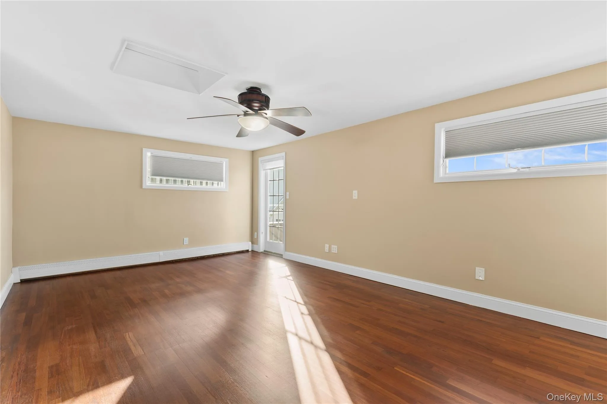 Empty room with dark wood-style flooring, a ceiling fan, and a baseboard radiator Empty room with dark wood-style flooring, a ceiling fan, and a baseboard radiator