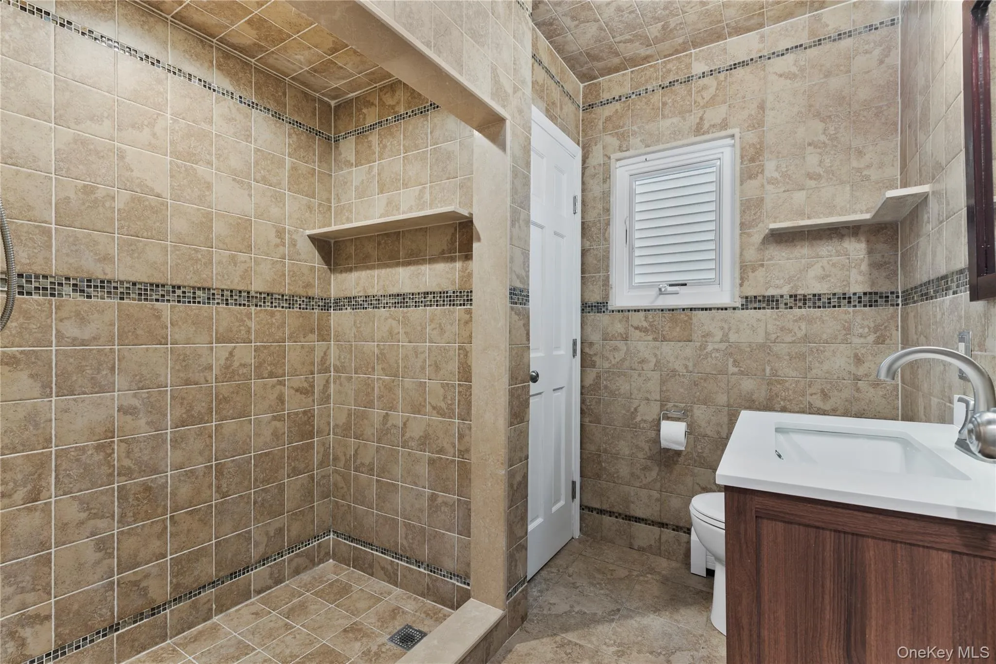 Full bath featuring vanity, a shower stall, and tile walls Full bath featuring vanity, a shower stall, and tile walls