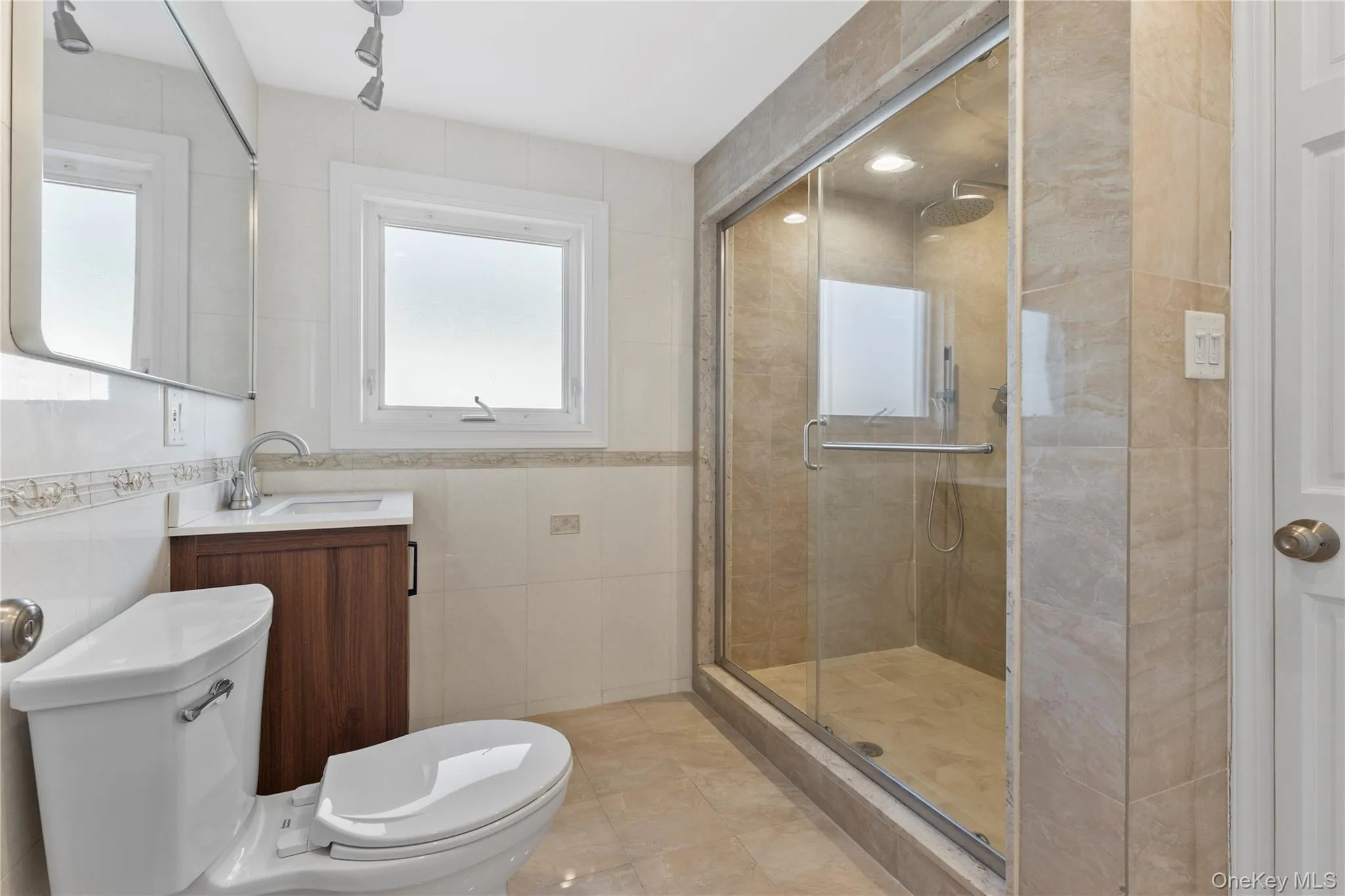Full bath featuring tile walls, a stall shower, and vanity Full bath featuring tile walls, a stall shower, and vanity