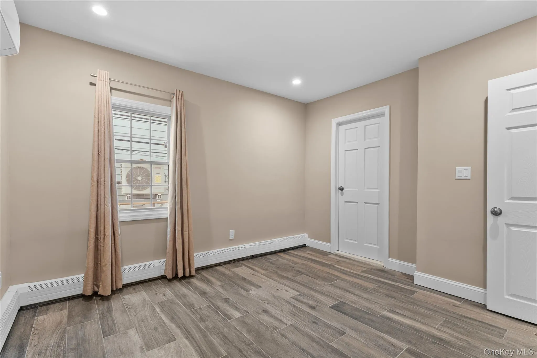 Empty room featuring wood finish floors, a baseboard heating unit, and recessed lighting Empty room featuring wood finish floors, a baseboard heating unit, and recessed lighting