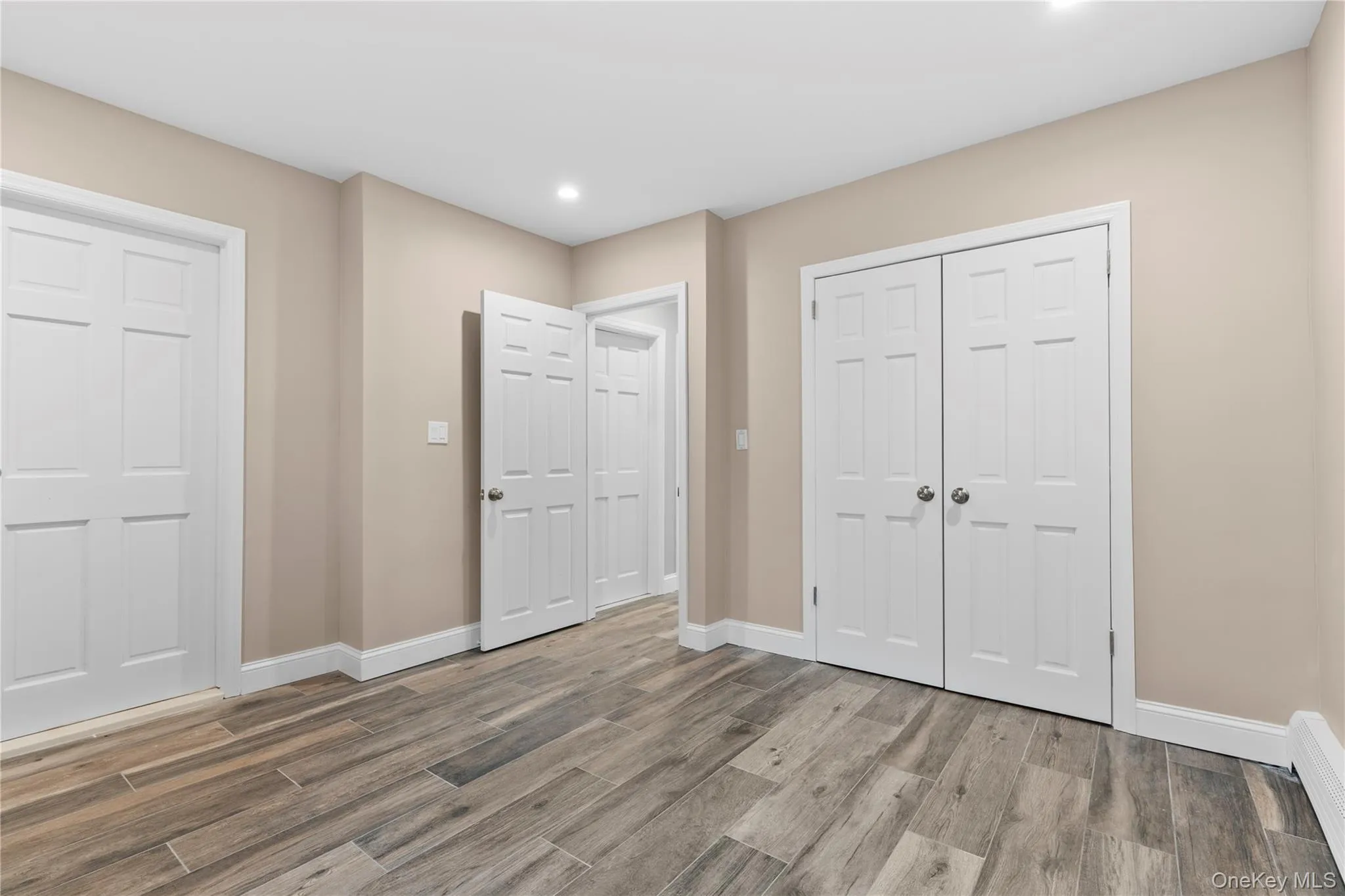 Unfurnished bedroom with wood finished floors, recessed lighting, and a baseboard radiator Unfurnished bedroom with wood finished floors, recessed lighting, and a baseboard radiator