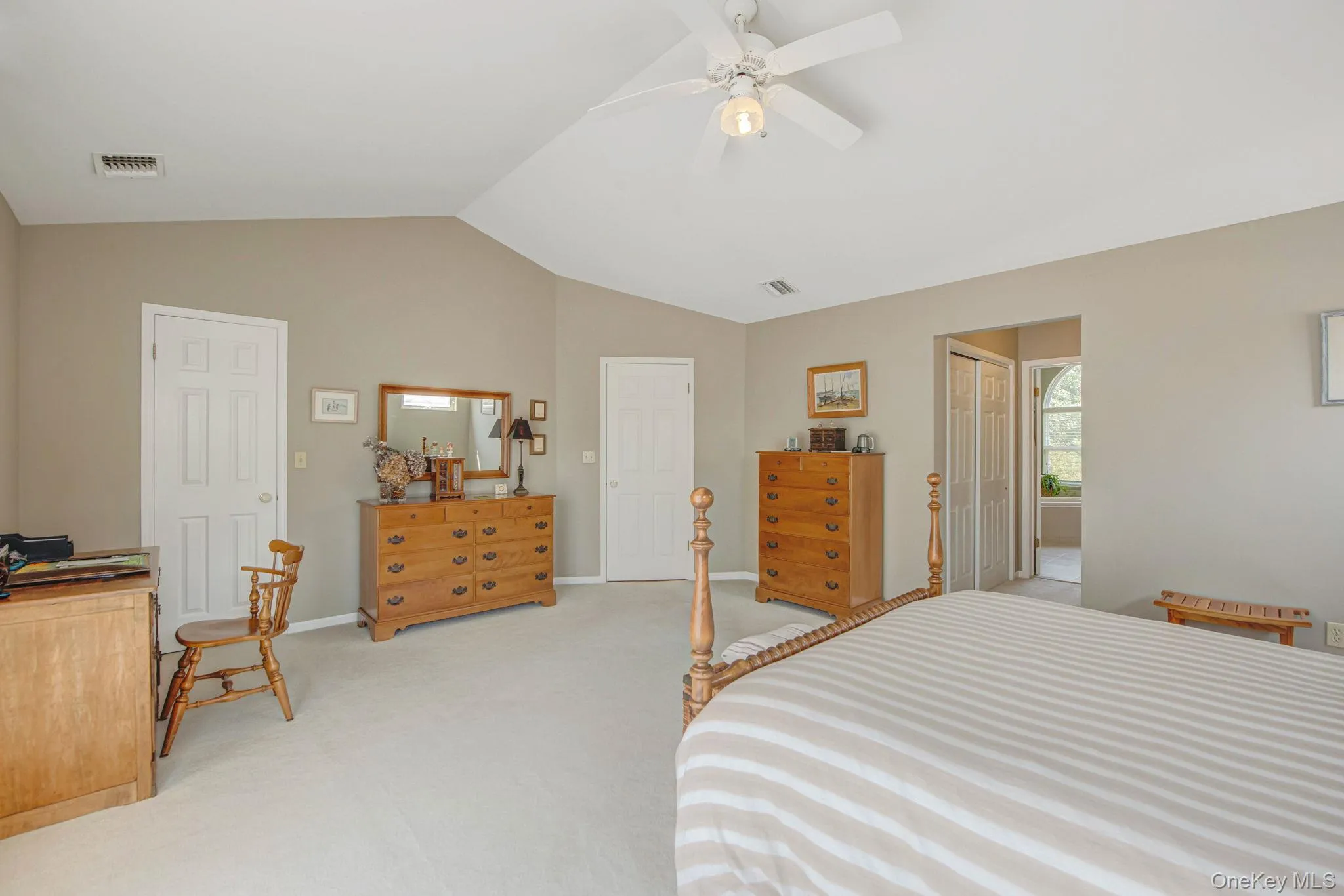 Bedroom with vaulted ceiling, light colored carpet, a closet, ceiling fan, and ensuite bath Bedroom with vaulted ceiling, light colored carpet, a closet, ceiling fan, and ensuite bath
