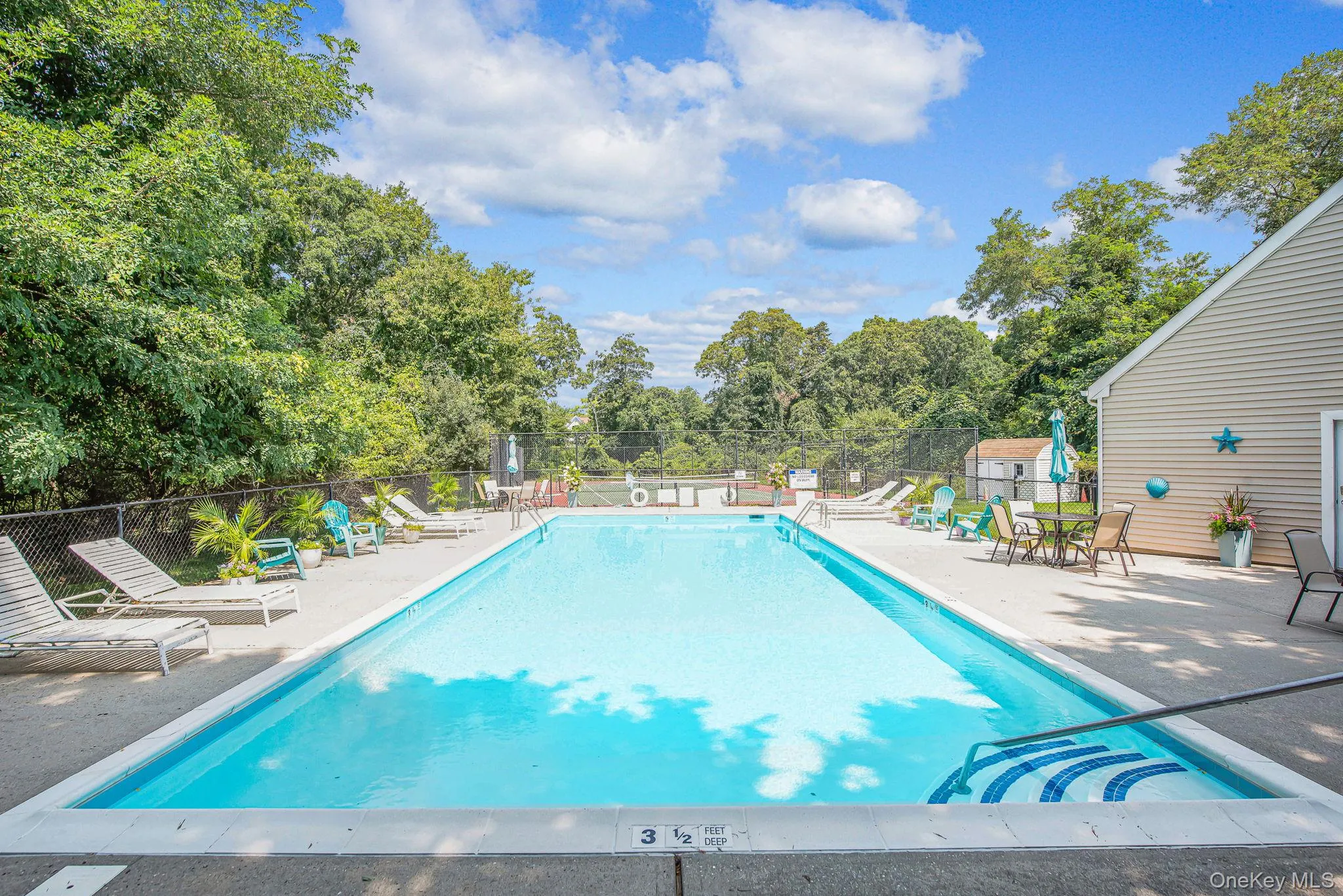 Community pool with a patio area and view of scattered trees Community pool with a patio area and view of scattered trees