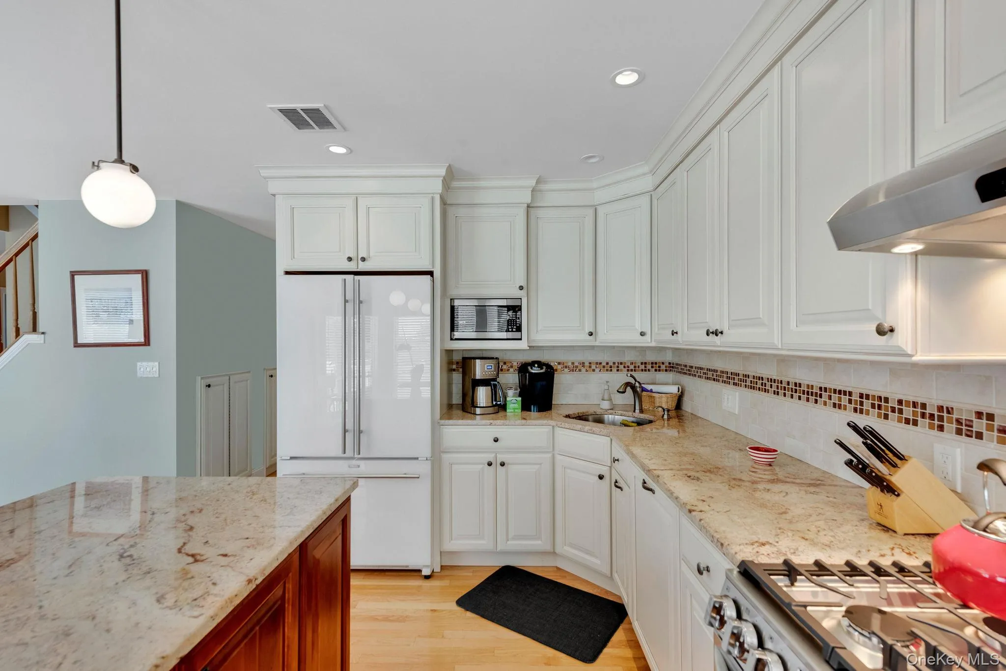 Kitchen with light stone counters, stainless steel appliances, pendant lighting, white cabinetry, and recessed lighting Kitchen with light stone counters, stainless steel appliances, pendant lighting, white cabinetry, and recessed lighting