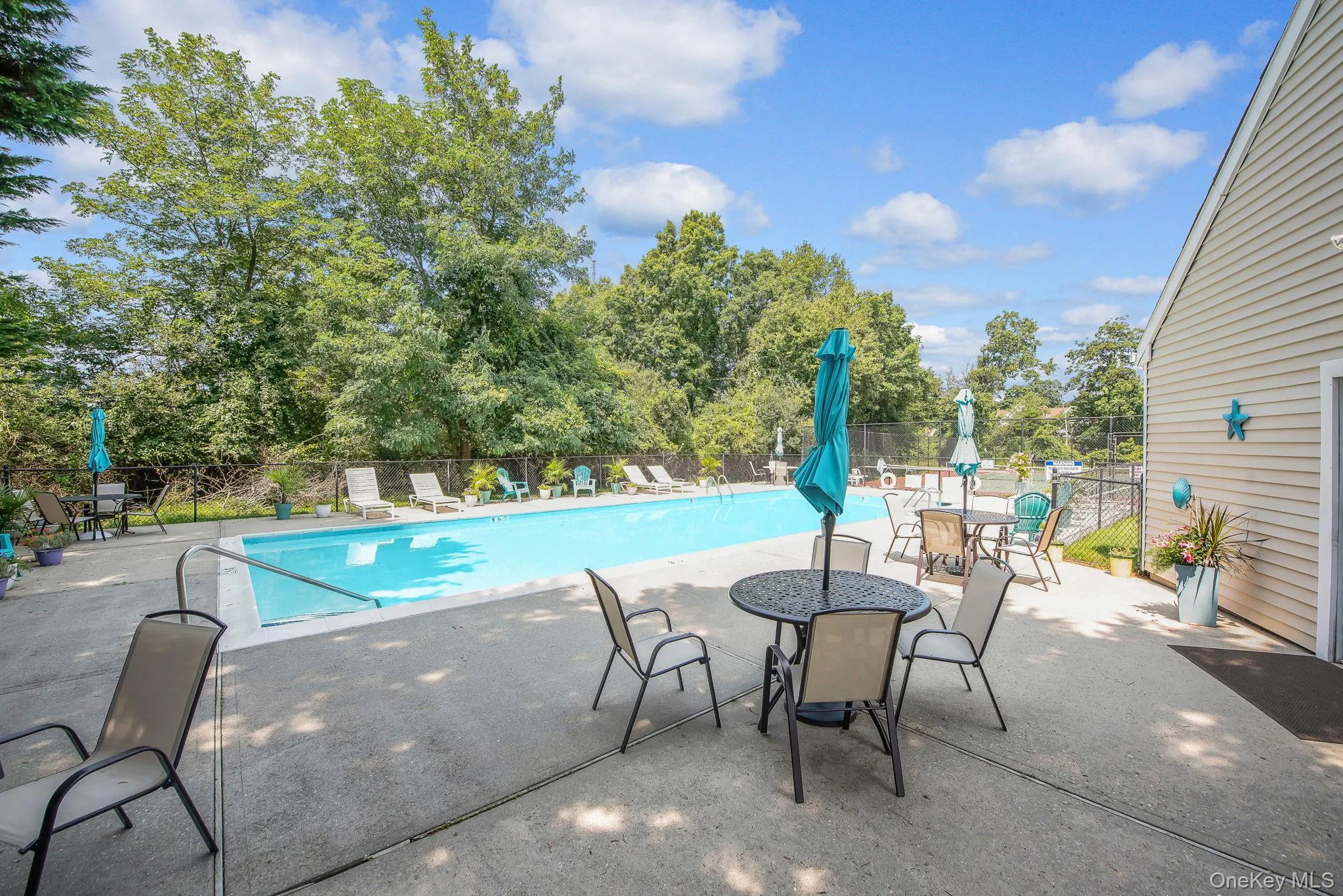 Community pool with a patio area and outdoor dining area Community pool with a patio area and outdoor dining area