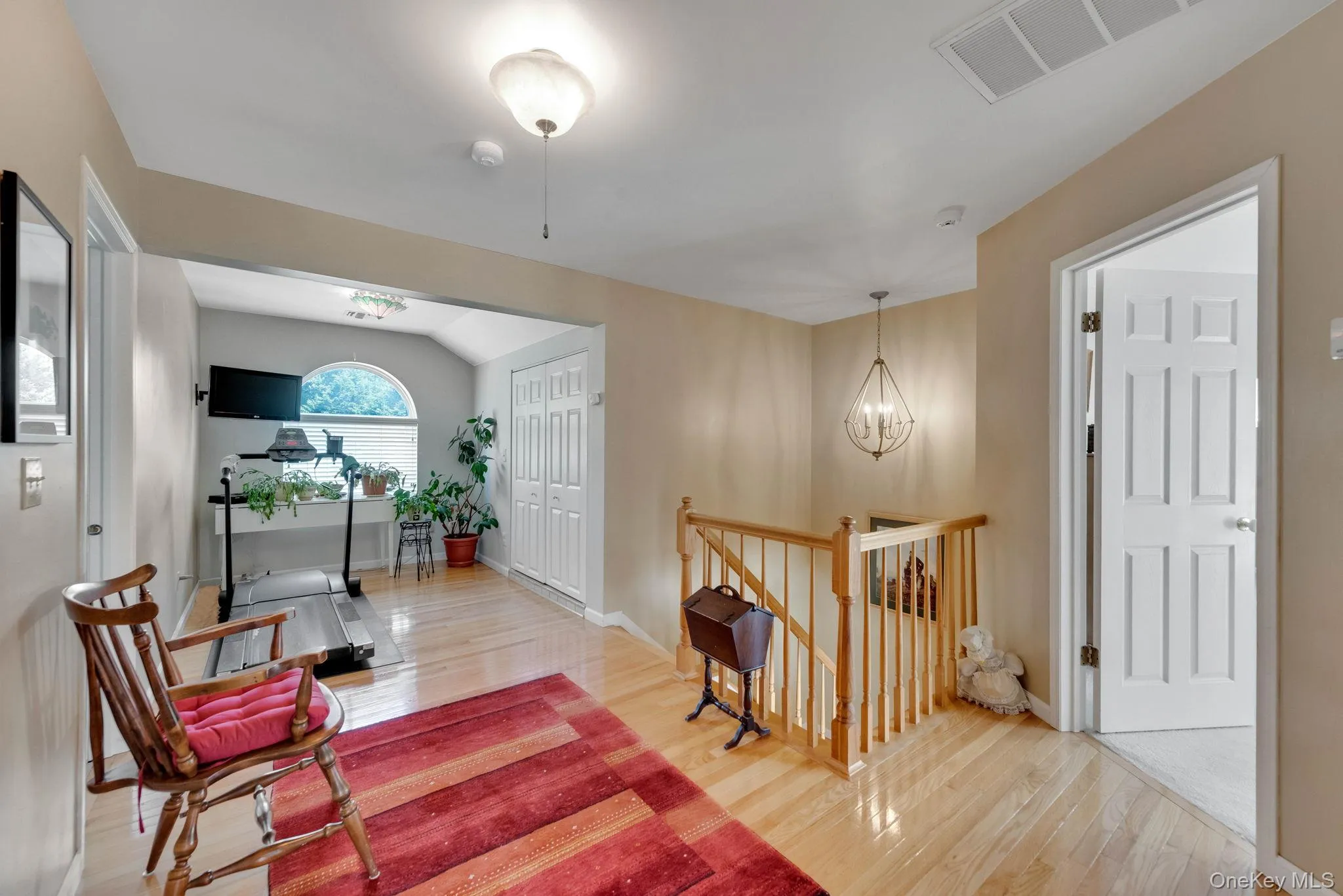 Corridor with an upstairs landing, light wood-style flooring, a chandelier, and lofted ceiling Corridor with an upstairs landing, light wood-style flooring, a chandelier, and lofted ceiling