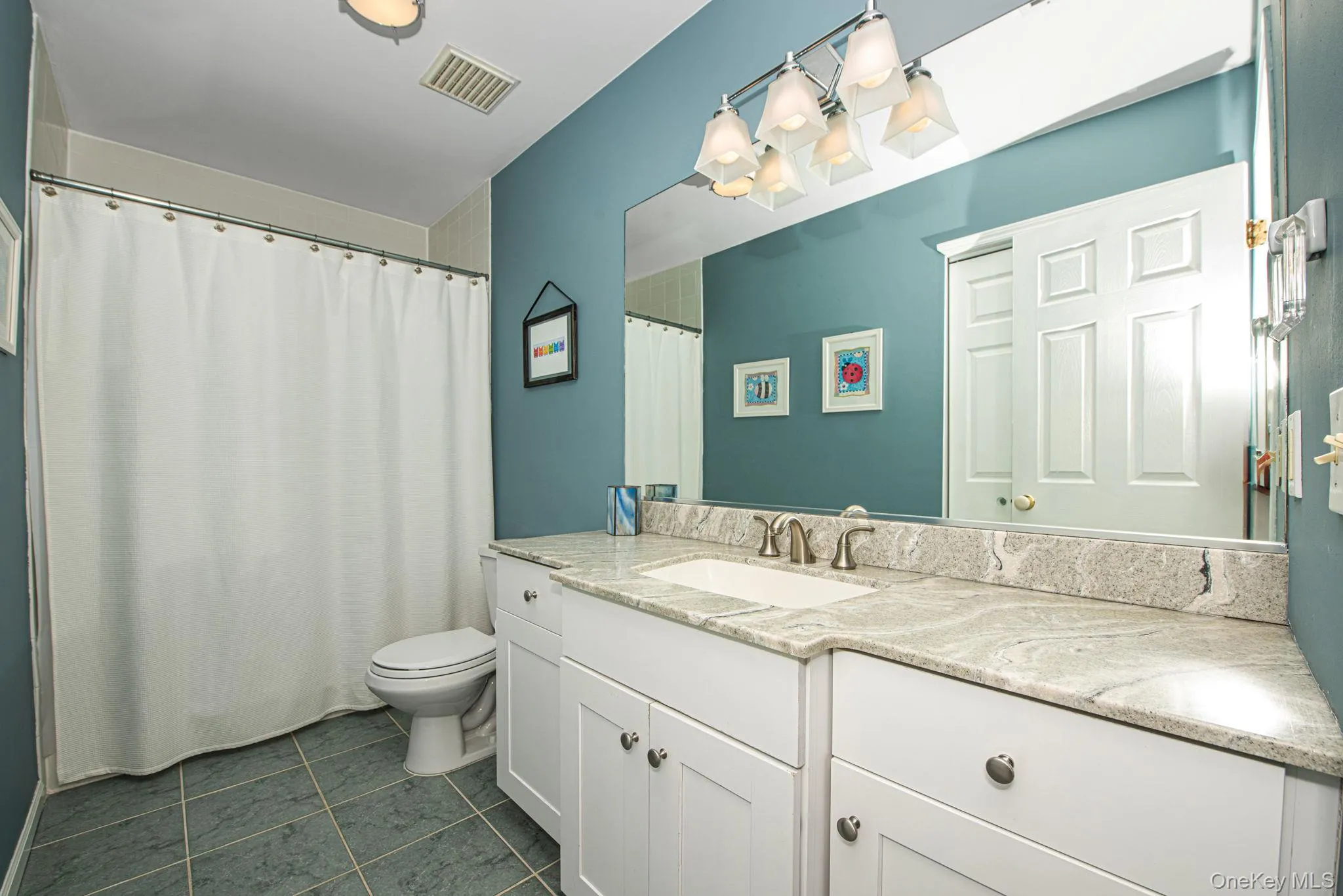 Full bath with vanity, a shower with shower curtain, and dark tile patterned floors Full bath with vanity, a shower with shower curtain, and dark tile patterned floors