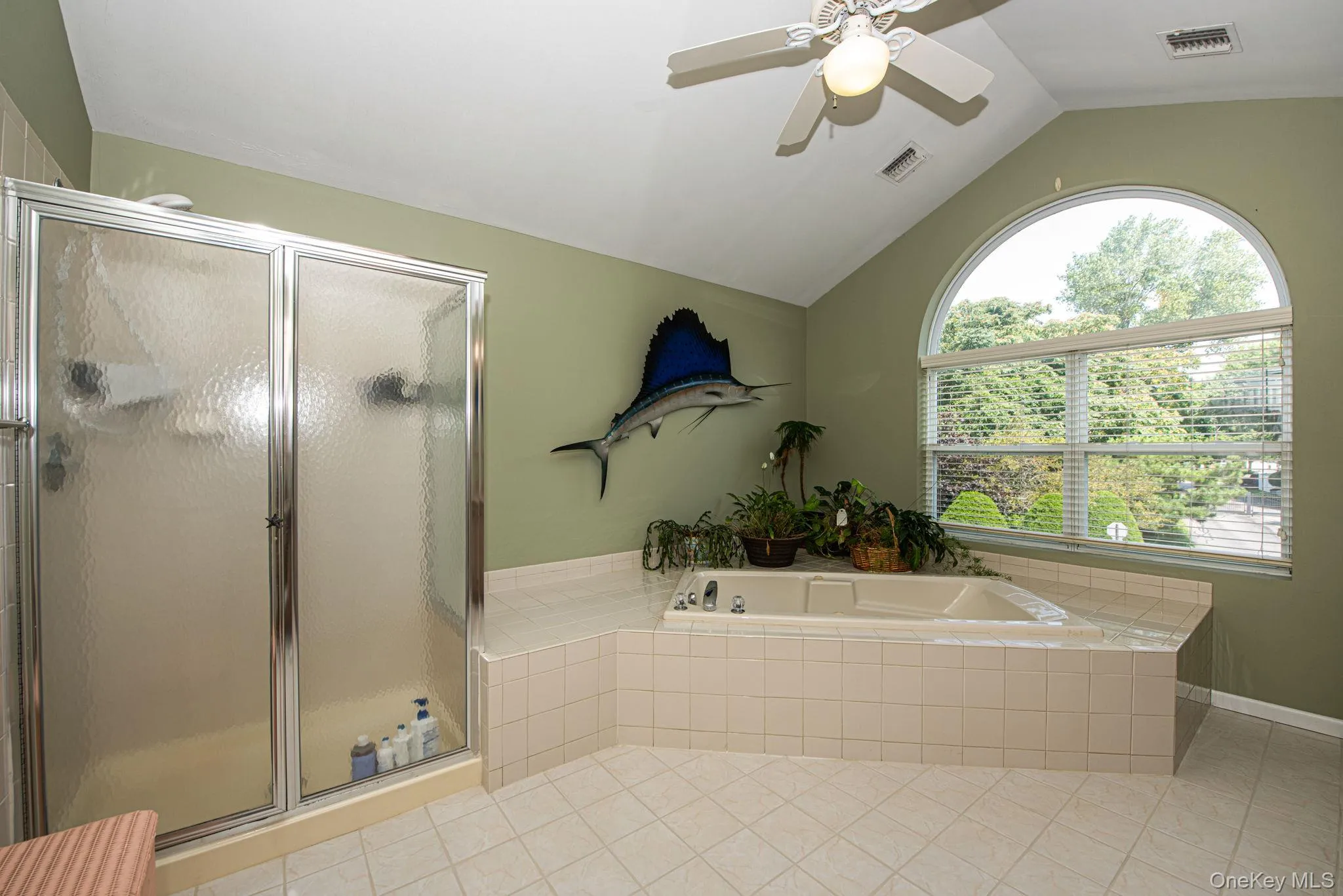 Bathroom featuring lofted ceiling, a shower stall, light tile patterned floors, a bath, and ceiling fan Bathroom featuring lofted ceiling, a shower stall, light tile patterned floors, a bath, and ceiling fan