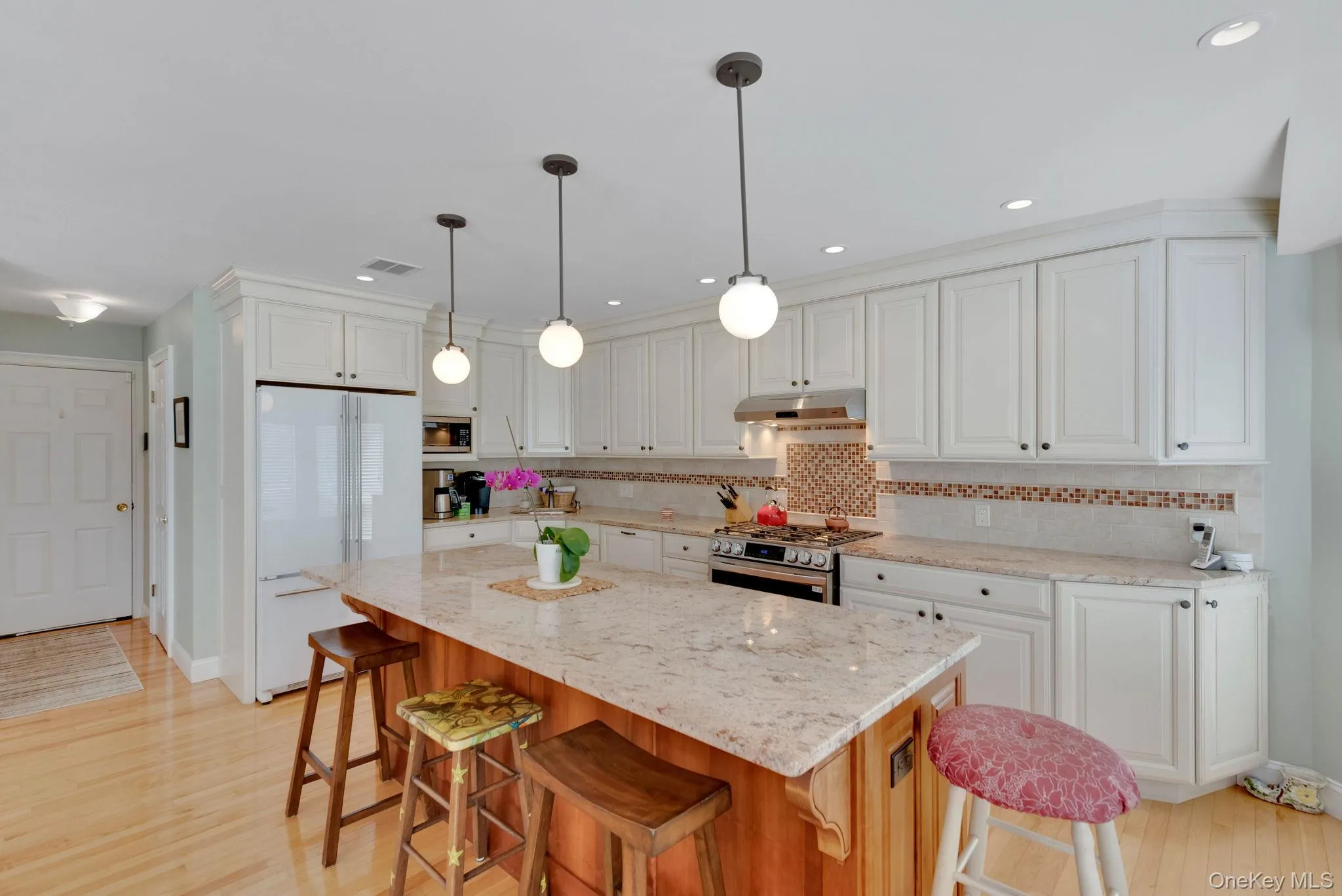 Kitchen with a breakfast bar, appliances with stainless steel finishes, light stone countertops, decorative light fixtures, and recessed lighting Kitchen with a breakfast bar, appliances with stainless steel finishes, light stone countertops, decorative light fixtures, and recessed lighting