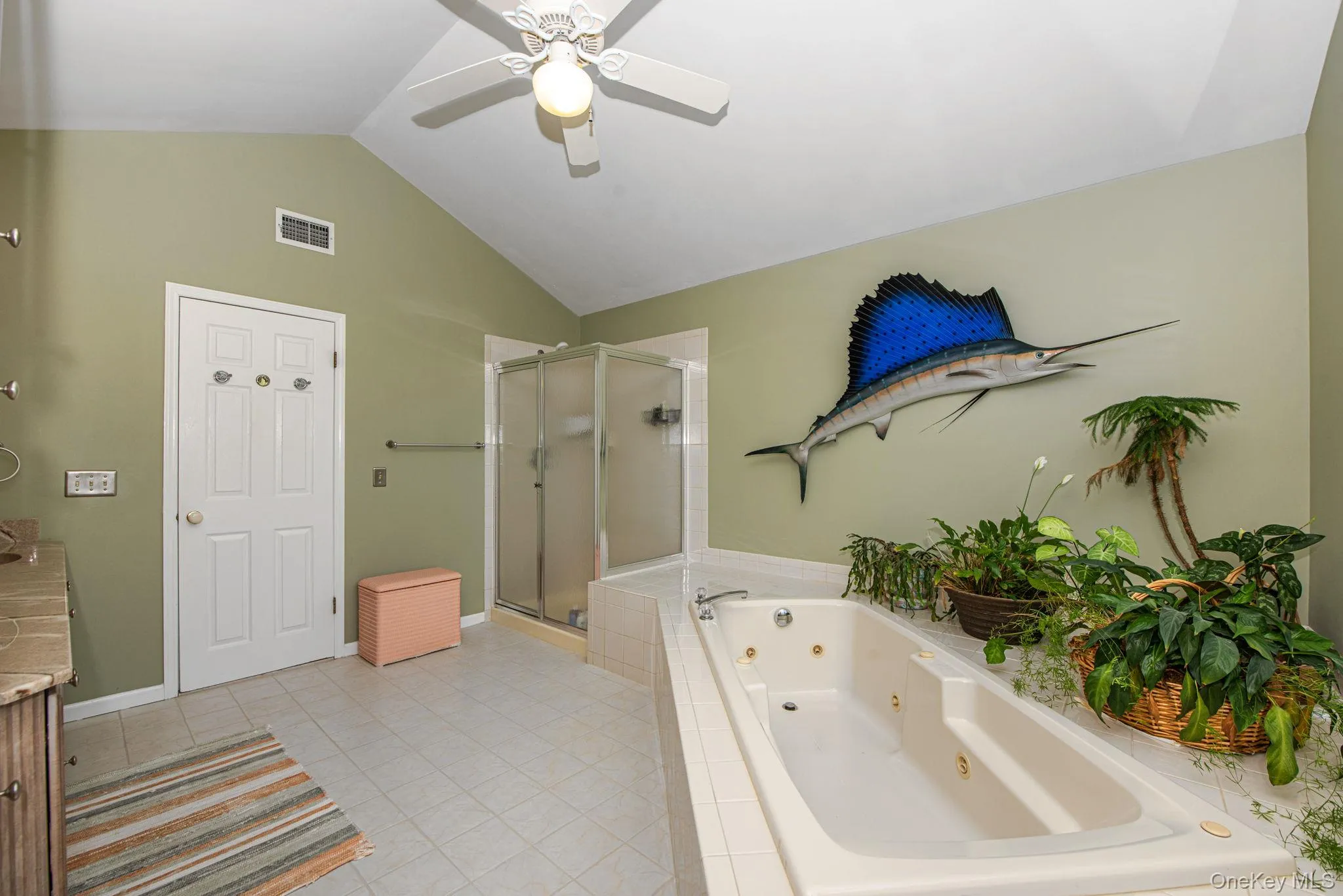 Full bath with a tub with jets, vanity, vaulted ceiling, a stall shower, and light tile patterned flooring Full bath with a tub with jets, vanity, vaulted ceiling, a stall shower, and light tile patterned flooring