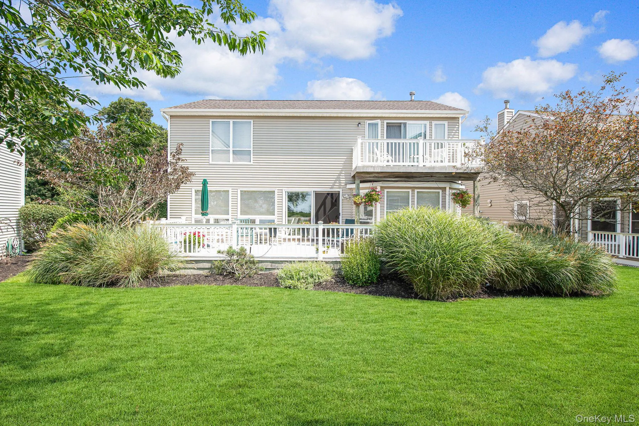 Rear view of property with a lawn, a deck, and a balcony Rear view of property with a lawn, a deck, and a balcony