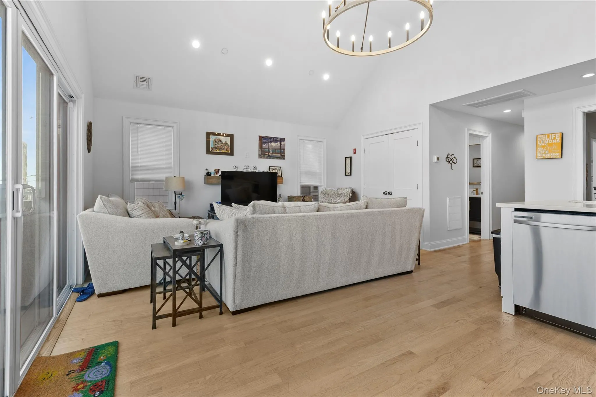 Living room featuring recessed lighting, high vaulted ceiling, a chandelier, and light wood-style flooring Living room featuring recessed lighting, high vaulted ceiling, a chandelier, and light wood-style flooring