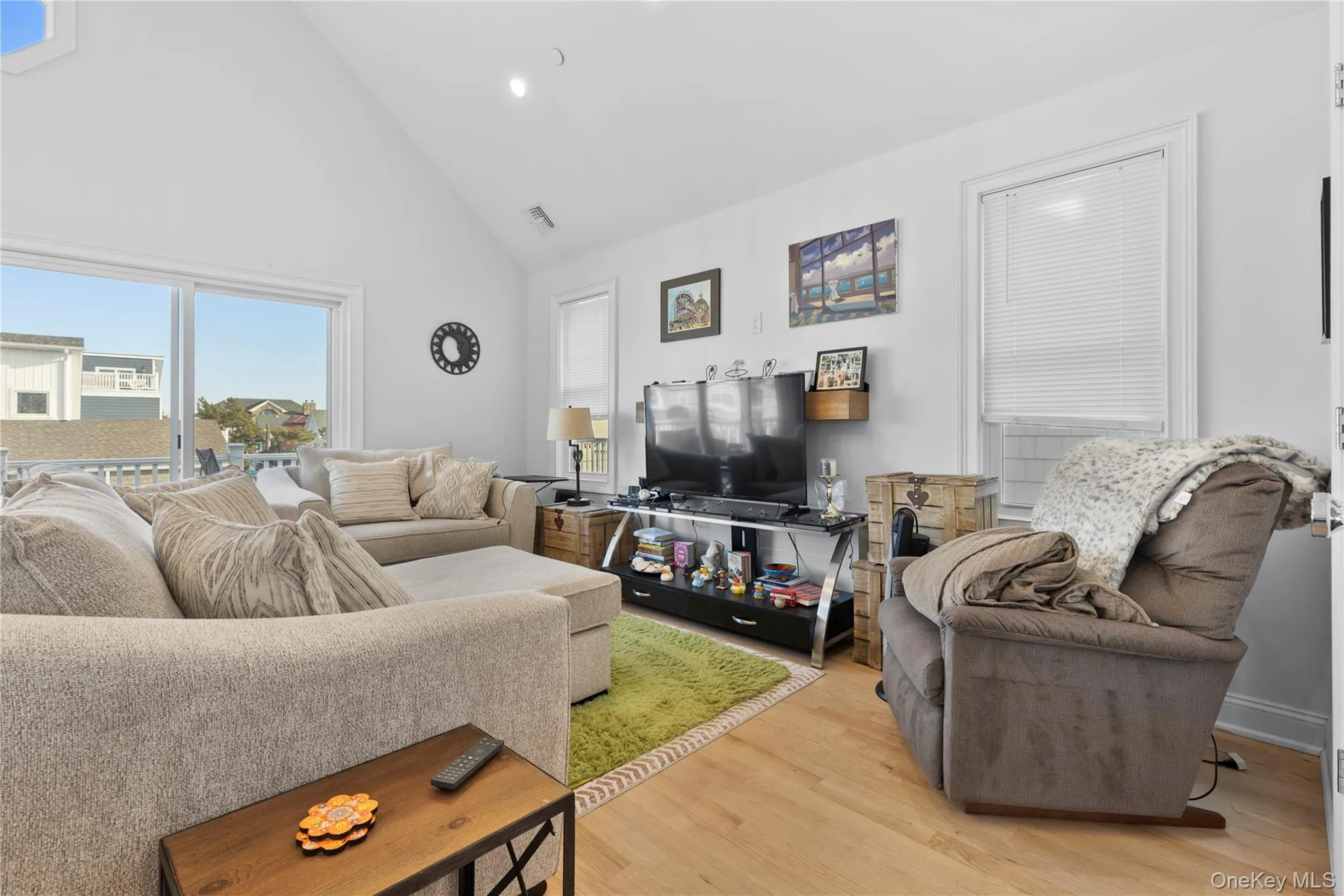 Living room with high vaulted ceiling, wood finished floors, and recessed lighting Living room with high vaulted ceiling, wood finished floors, and recessed lighting